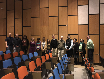Group of ten people standing in a theater with empty colorful seats.