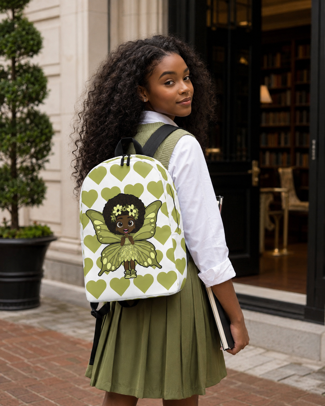 Cheerful Charlotte Pixie backpack featuring a Black girl pixie with green wings on the Coco Pixies signature heart pattern.
