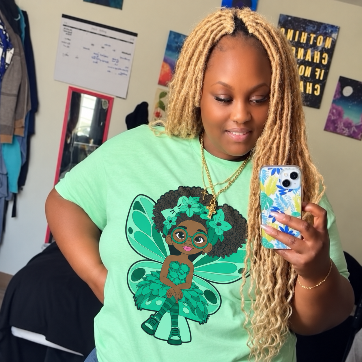 Black Woman standing in front of a mirror wearing her green Brilliant Bailey Pixie Signature Shirt - Coco Pixies Character Graphic T-Shirt, ADULT SIZE