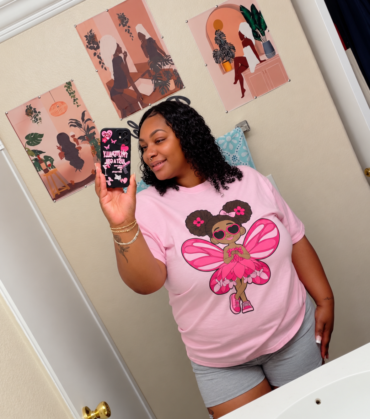 Black woman taking a selfie wearing her Glitzy Gracelynn Pixie Signature Shirt - Coco Pixies Character Graphic T-Shirt, ADULT SIZE