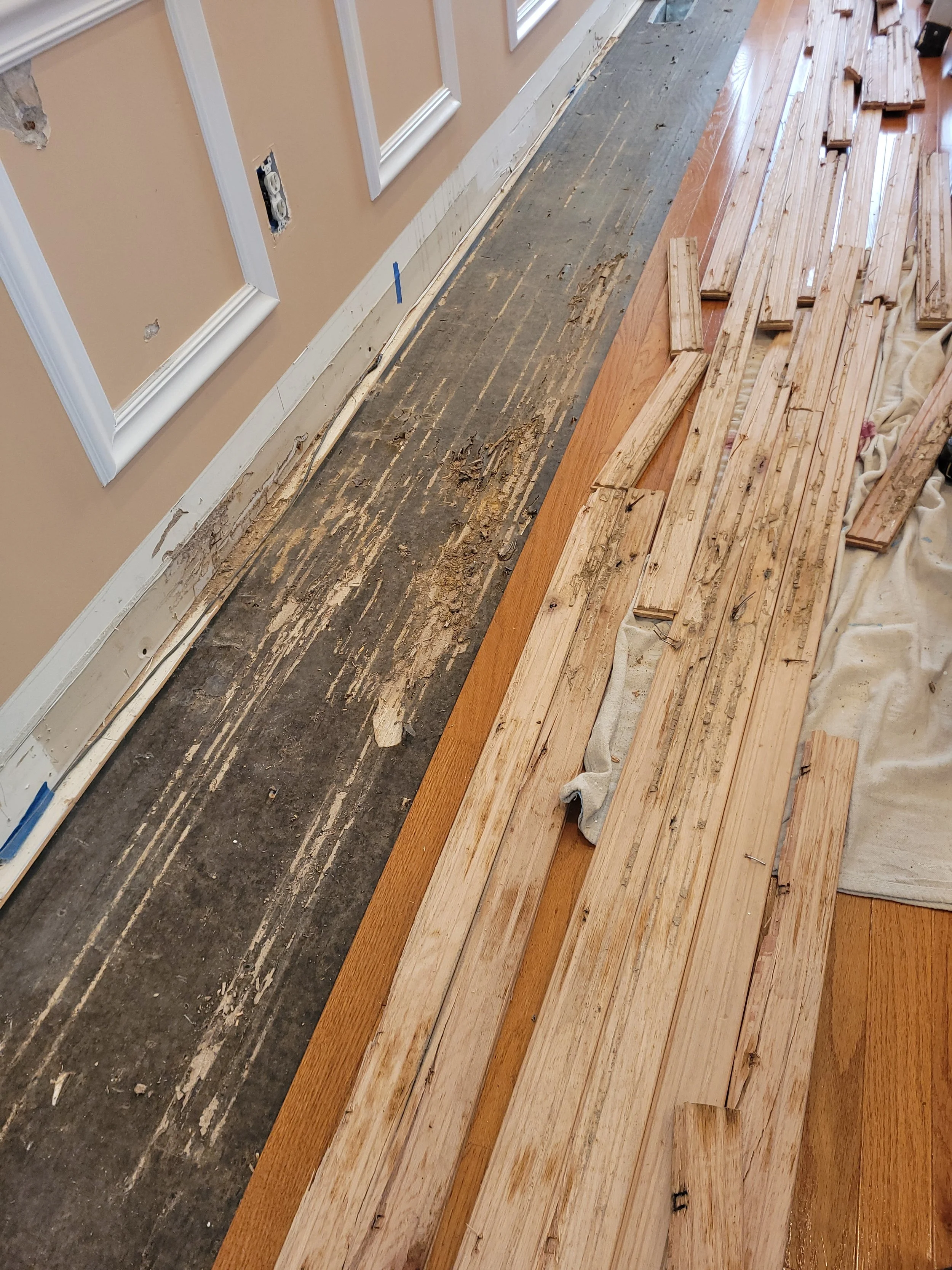 Floor renovation with partially removed old flooring and new hardwood planks ready to be installed.