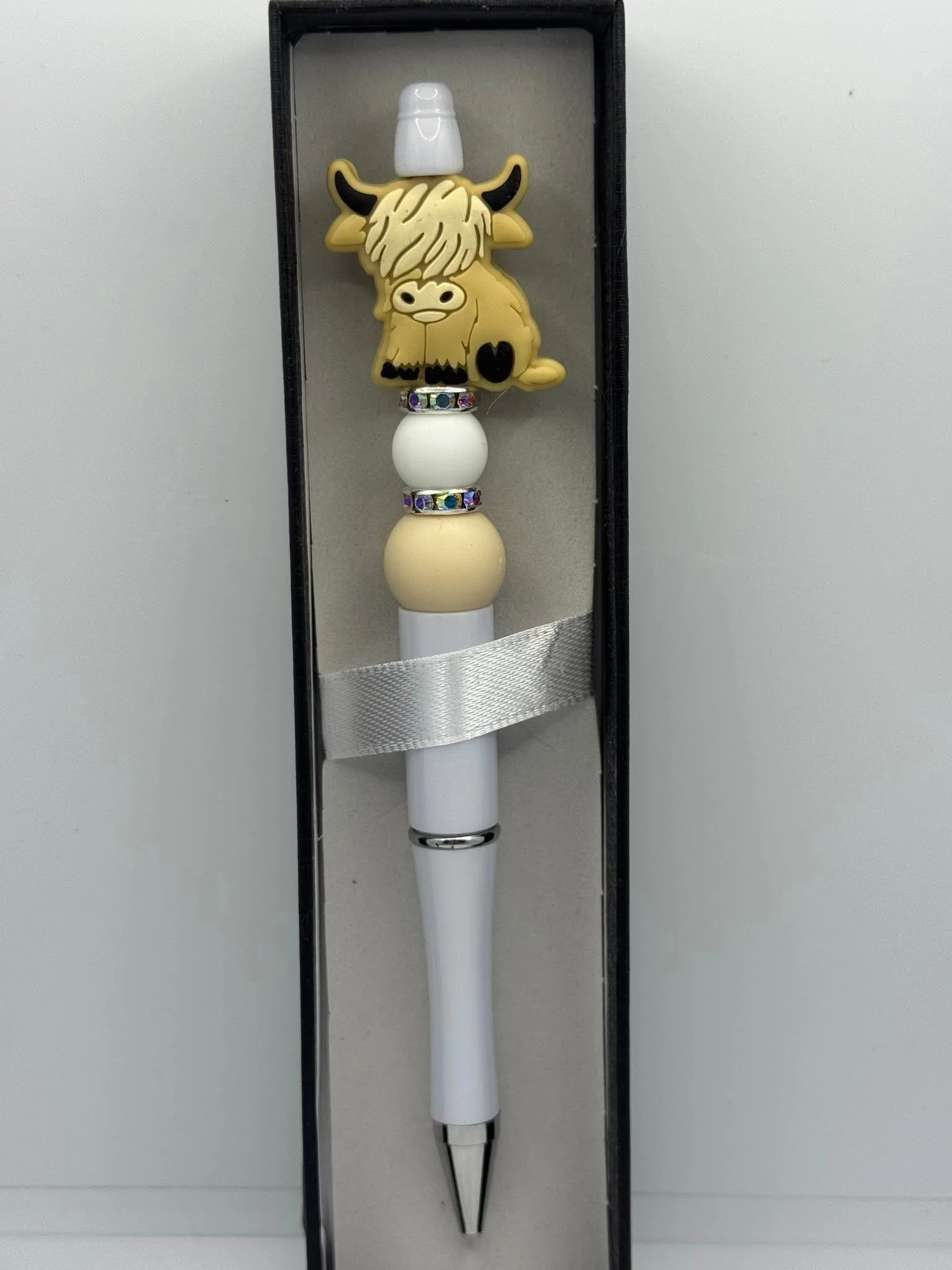 A pen with a cow-shaped topper in a black presentation box.