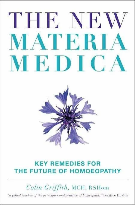 Cover of a book titled 'The New Materia Medica' with a blue flower illustration and subtitle 'Key Remedies for the Future of Homoeopathy' by Colin Griffith, featuring a quote from Positive Health.