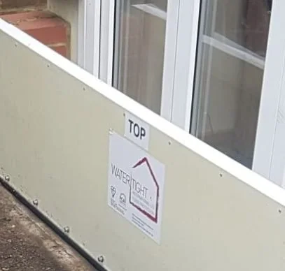 Sign on a balcony railing indicating the top of the water tight window installation.