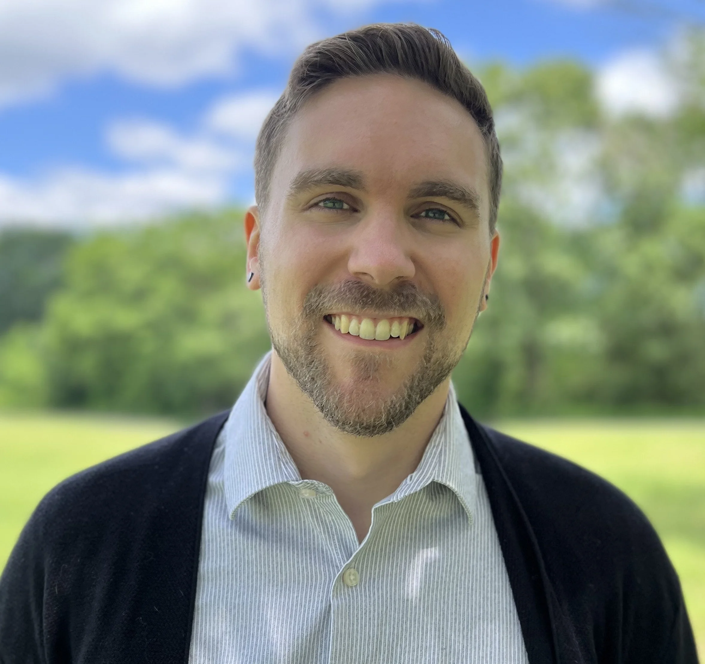 Smiling person outdoors with blurred green background