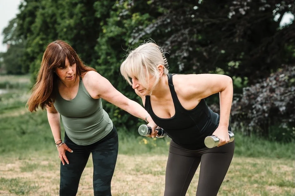A woman doing a weights-based PT session in a park