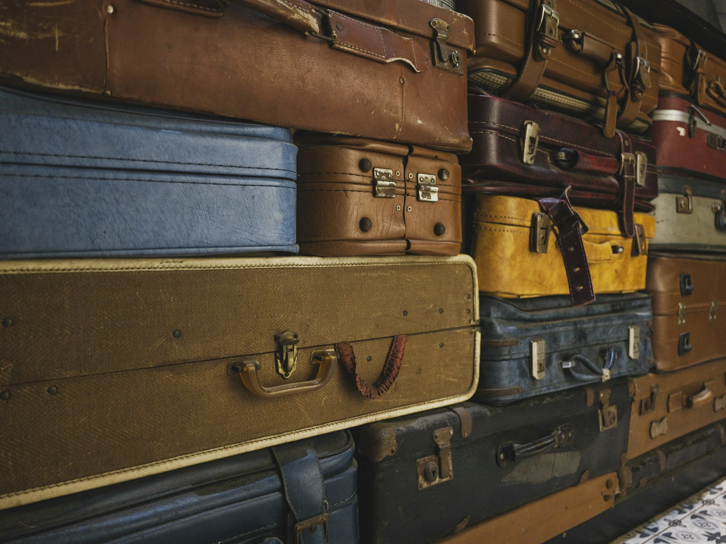 Stacked  suitcases in various colors and sizes.