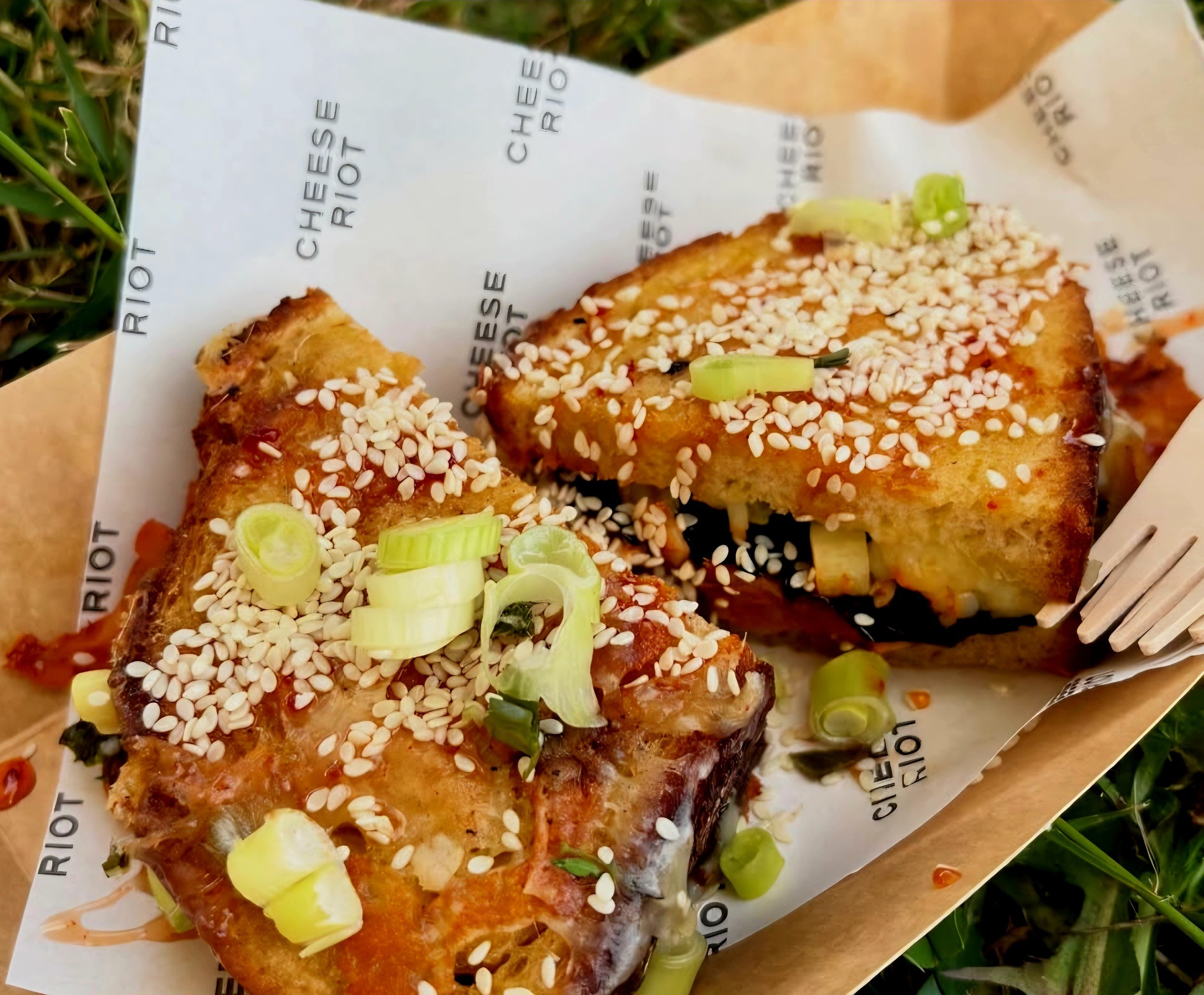 Cheese Riot Cheese Toastie served in an event bowl for weddings, festivals and parties, showing a korean themed cheese toastie with kimchi, crispy seaweed, gochujang honey and sesame seeds