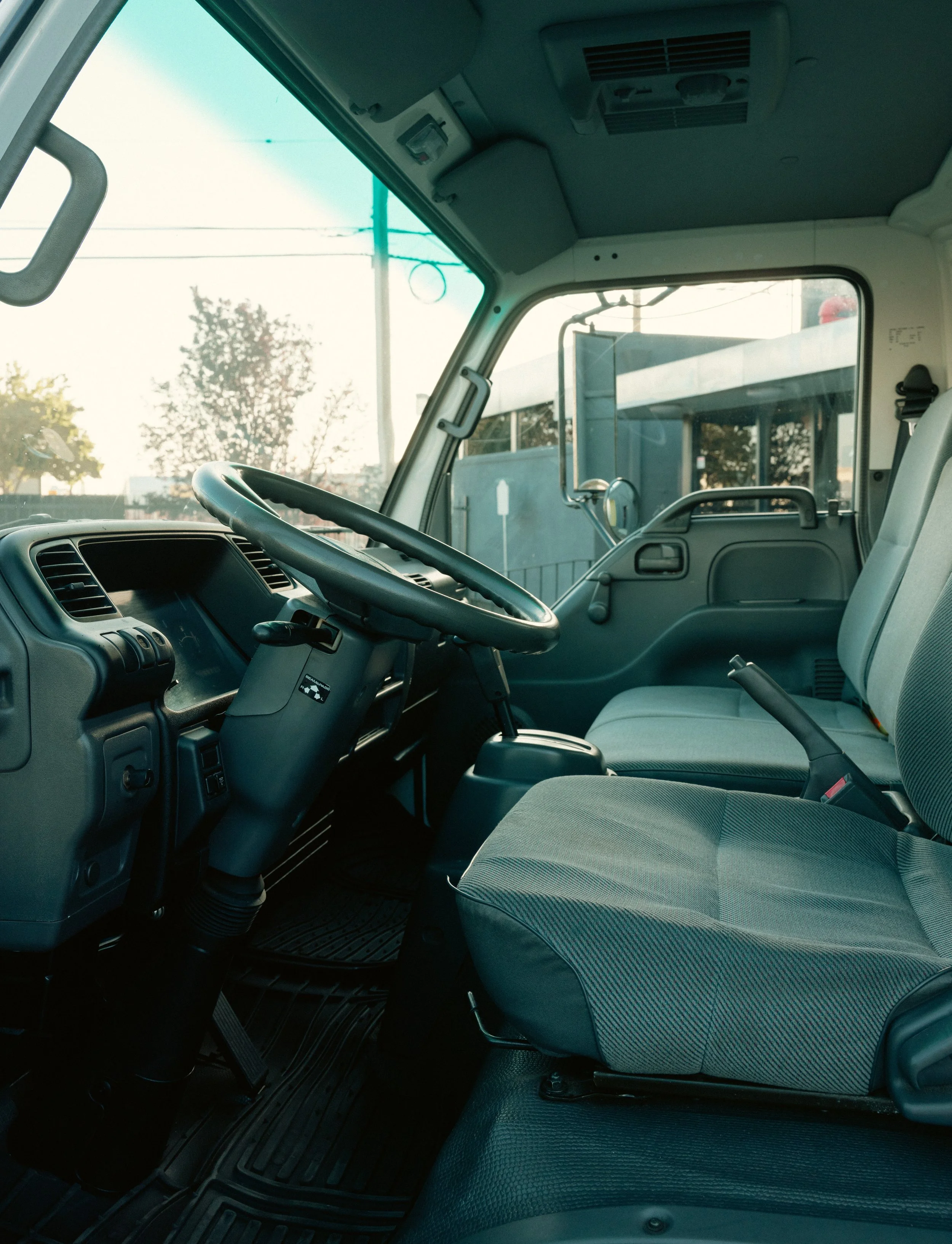 Interior of a commercial truck cabin with a steering wheel, dashboard, and passenger seat.