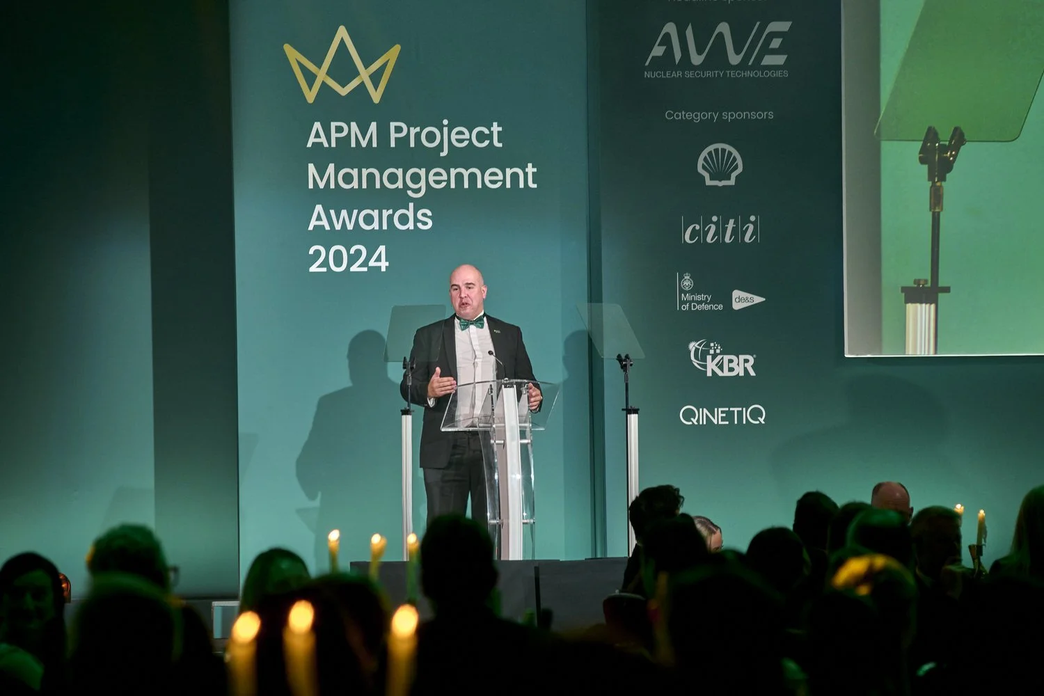 Man presenting on stage to a large audience during conference.