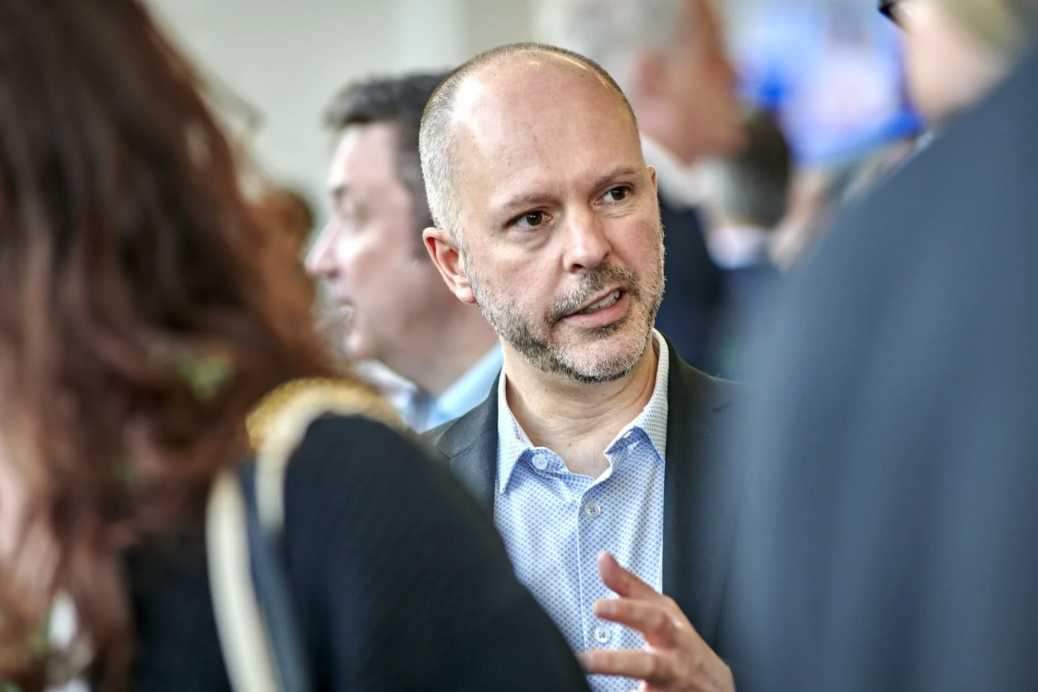 Man seen through the crowd talking with other delegates at a business event.