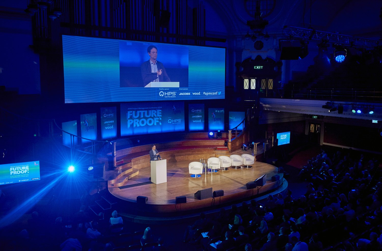Wide view of a large auditorium with stage and conference speaker.