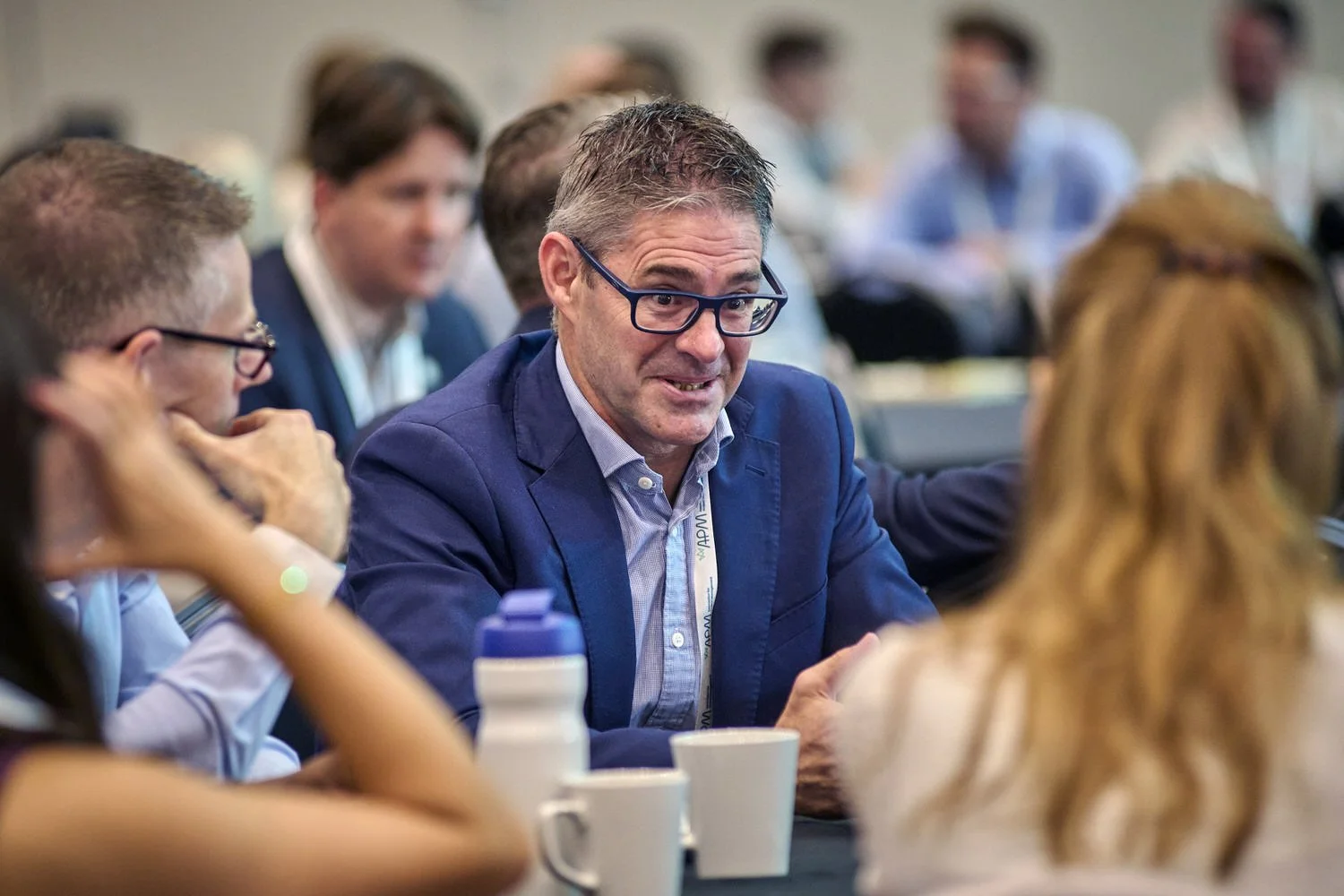 Man in the audience talking to colleagues during networking session.