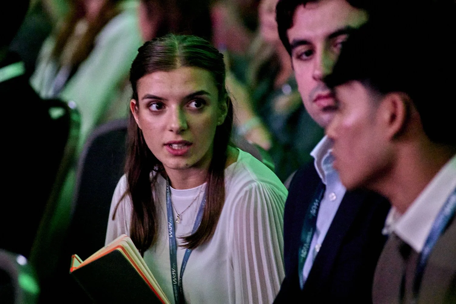Lady in audience looking at colleague under green lighting.