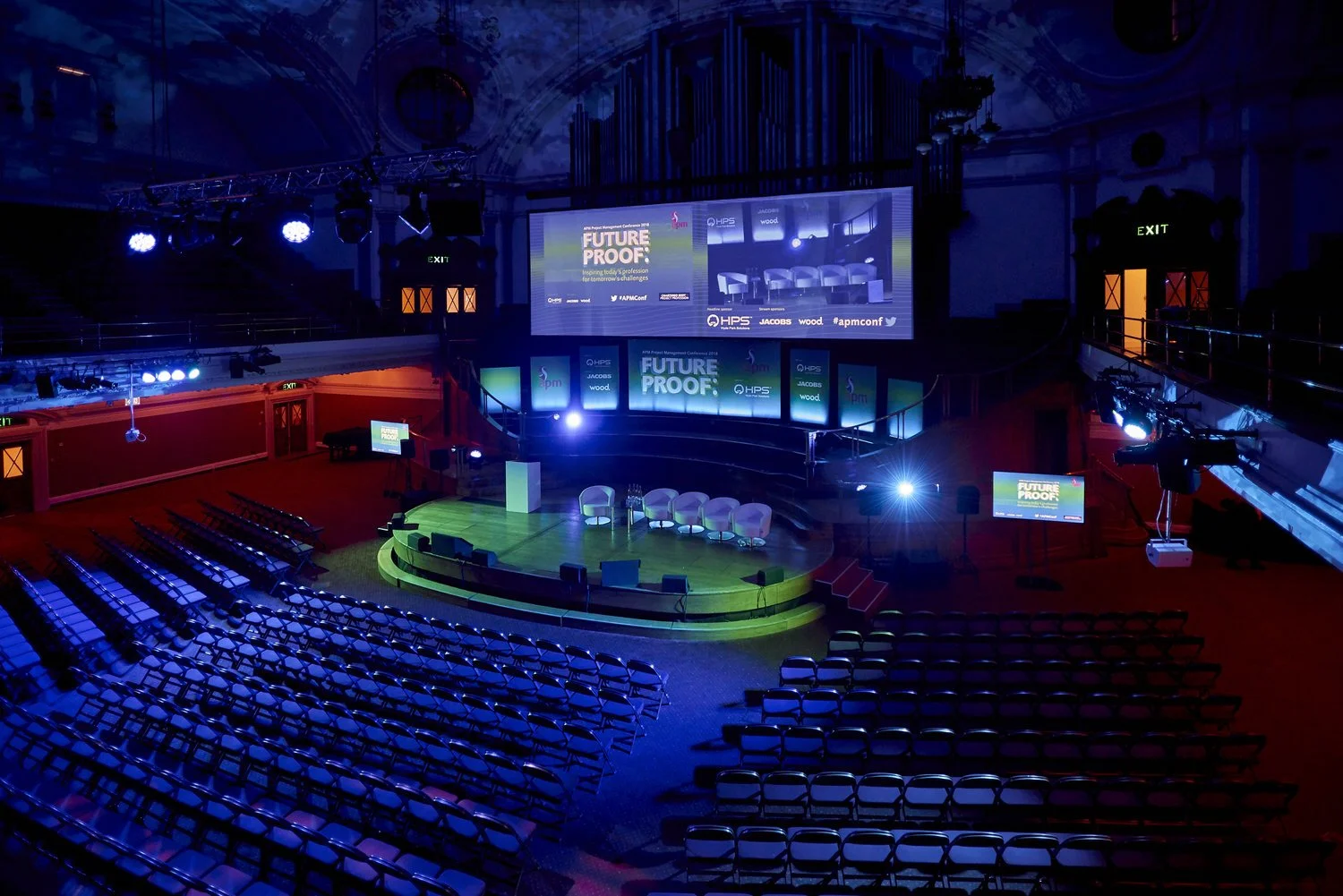 Moody view of a large auditorium with rows of empty seats before an event begins.