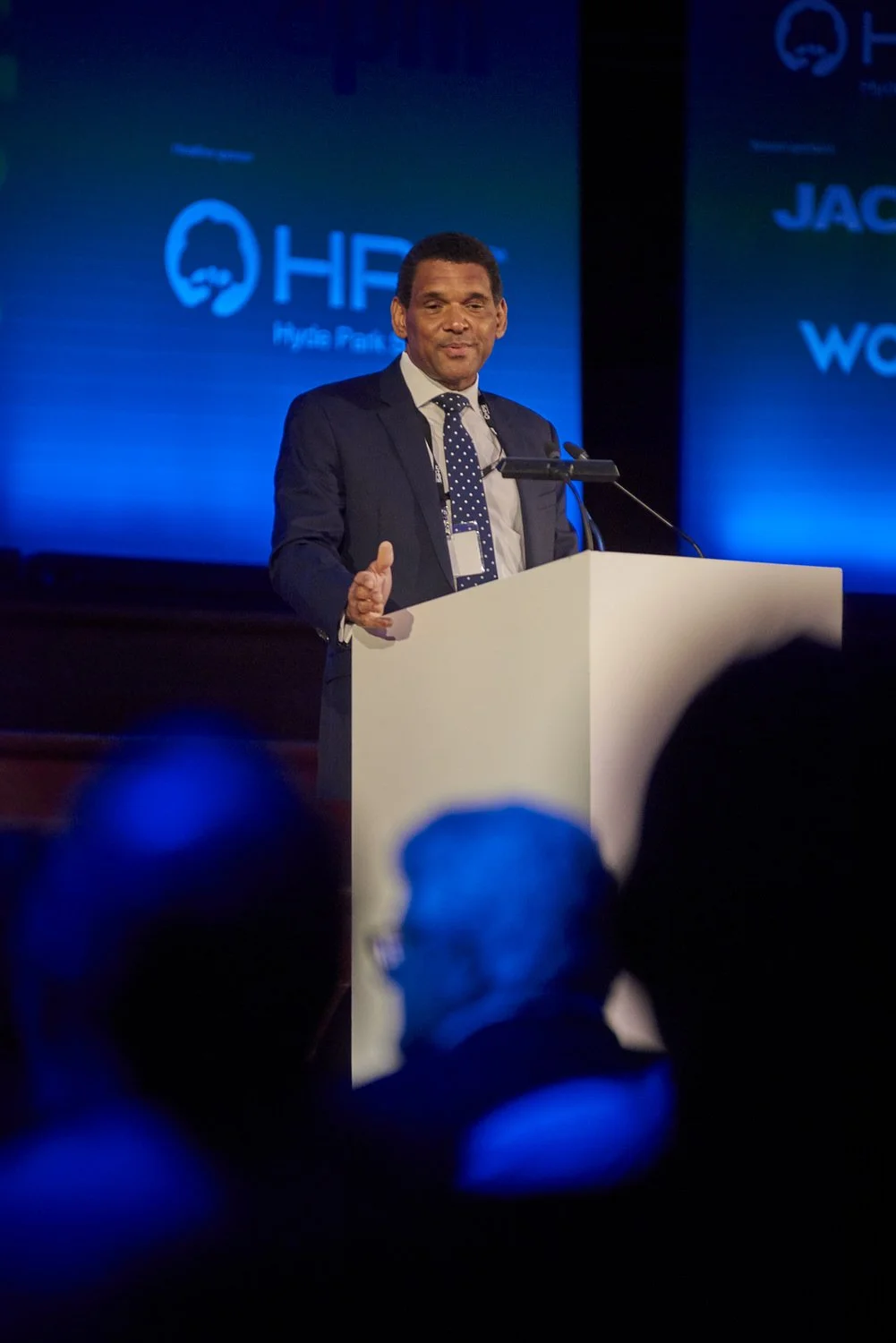 Male speaker at podium addressing an audience during a corporate event.