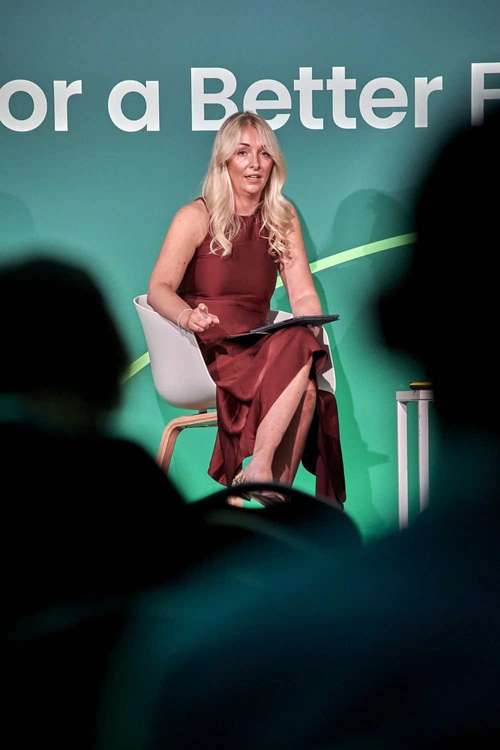 Lady speaking on stage wearing red.