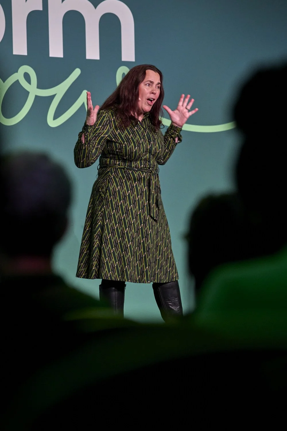 Lady standing on stage gesturing with her hands during presentation.