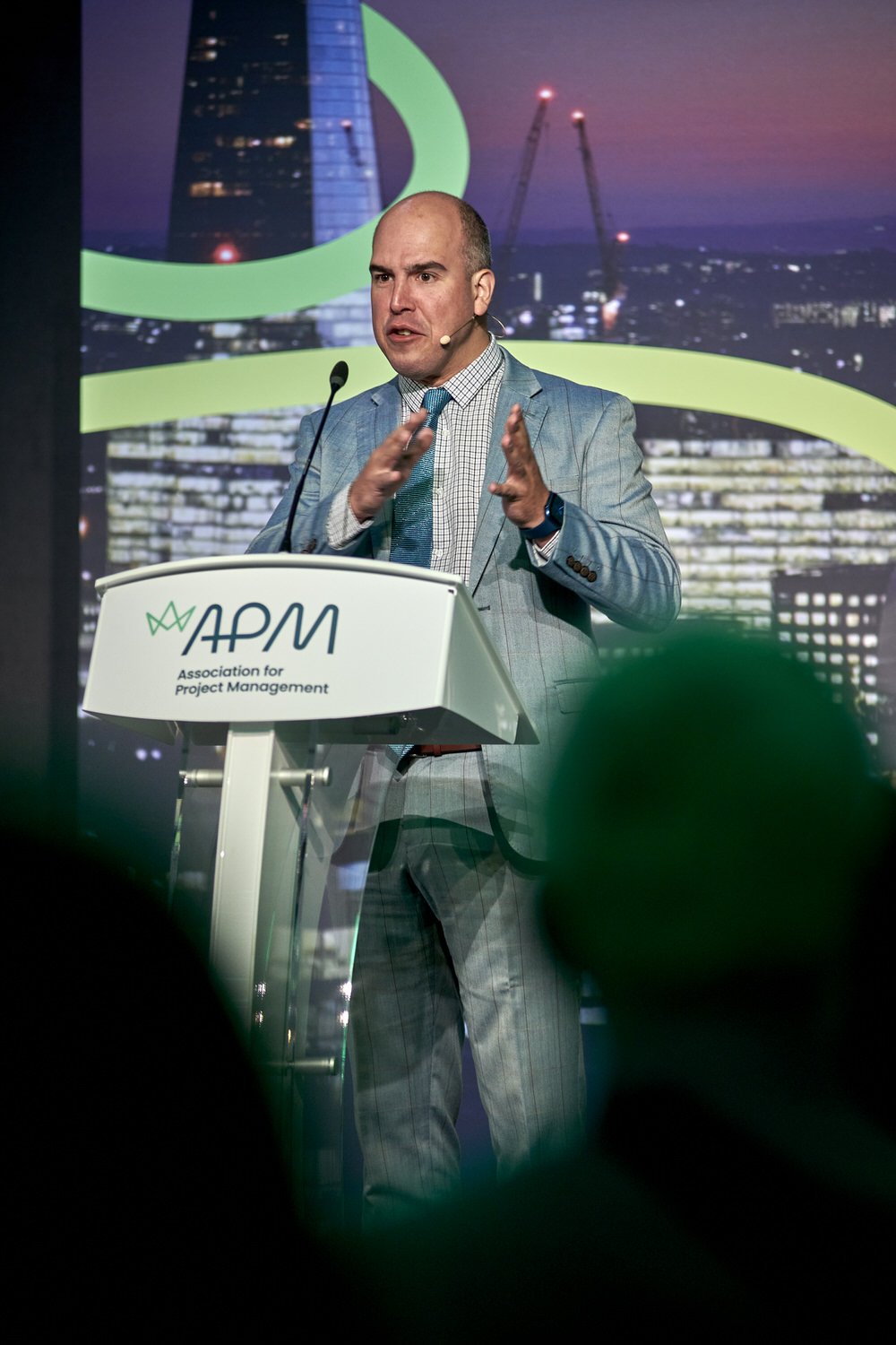 Male speaker delivering a talk at the APM podium during a conference.