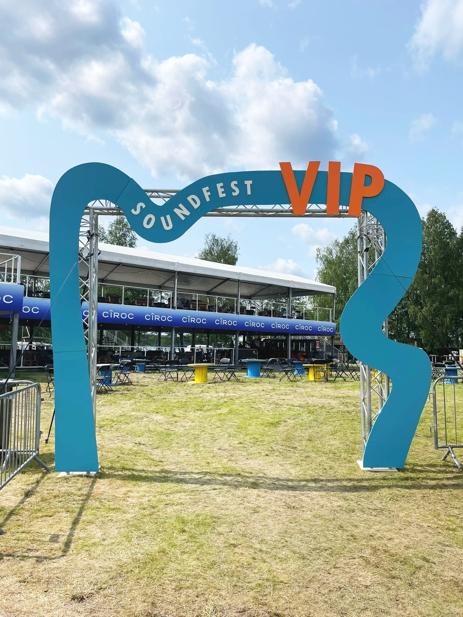 Soundfest VIP-alueen sisäänkäynti, suuri sininen rekvisiitta, jossa lukee 'Soundfest' ja 'VIP', ja takana on tapahtuma-alueen katsomo ja järjestetty istuma-alue.
