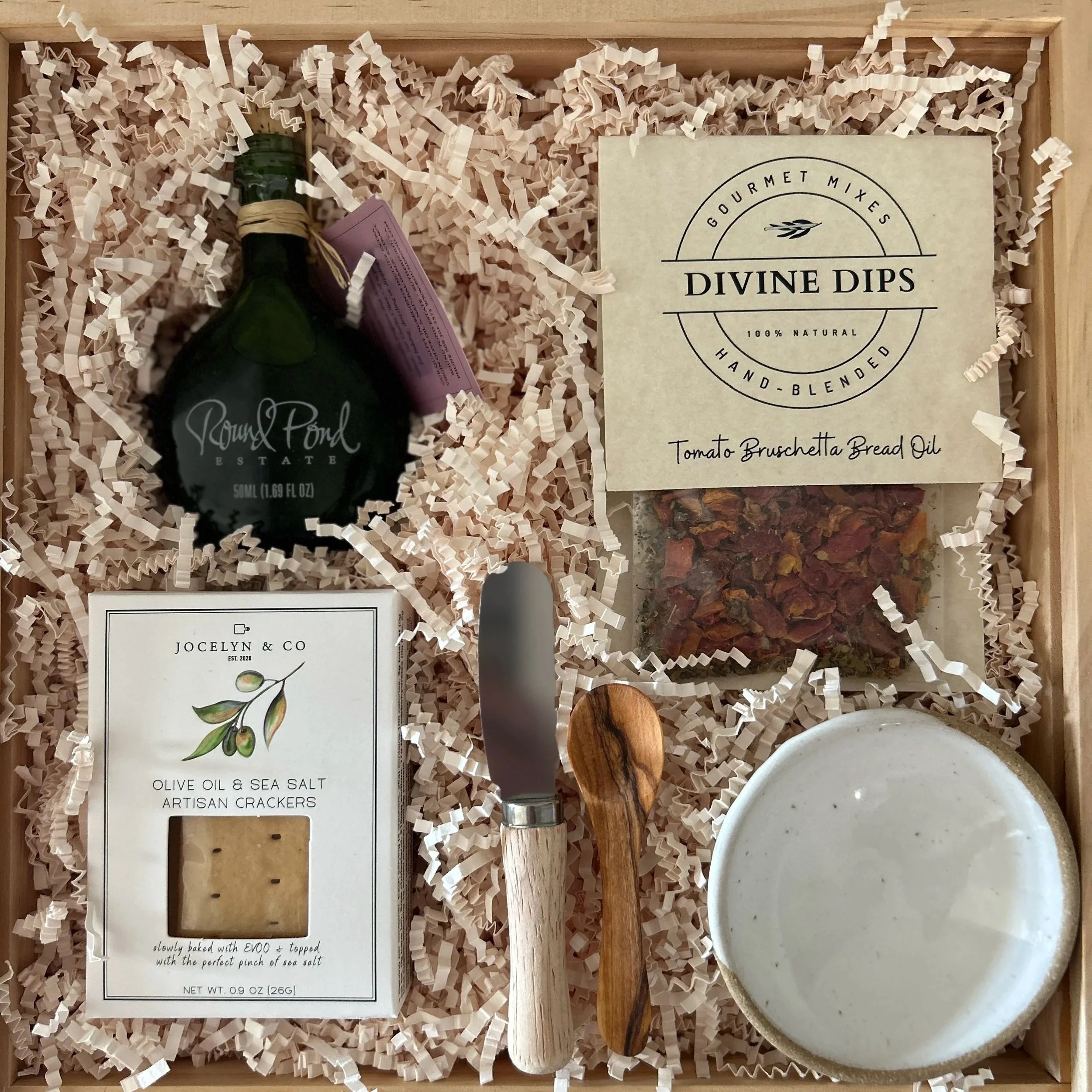 Gift box with various gift items with a purple bow and dried flowers