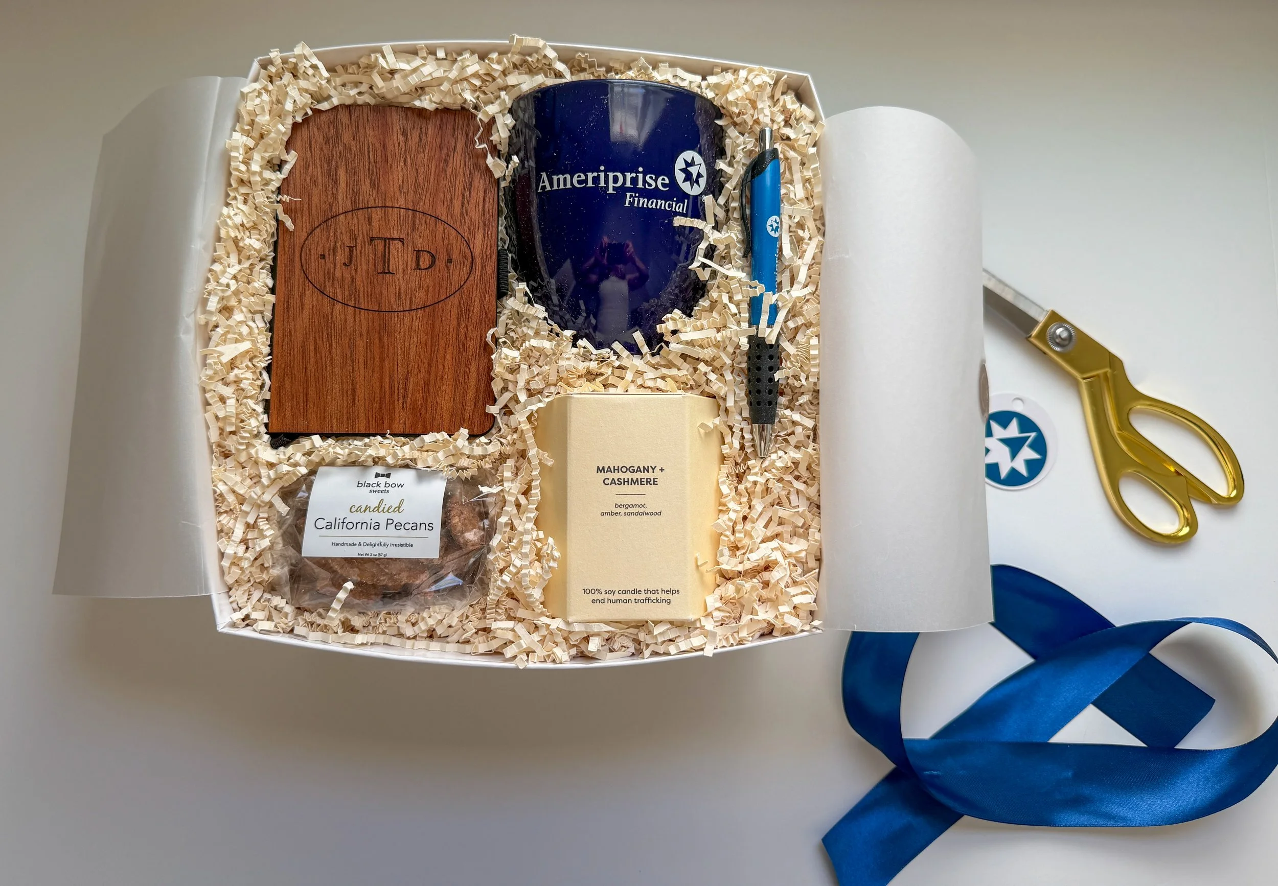 a gift box with an engraved notebook branded mug candle and nuts