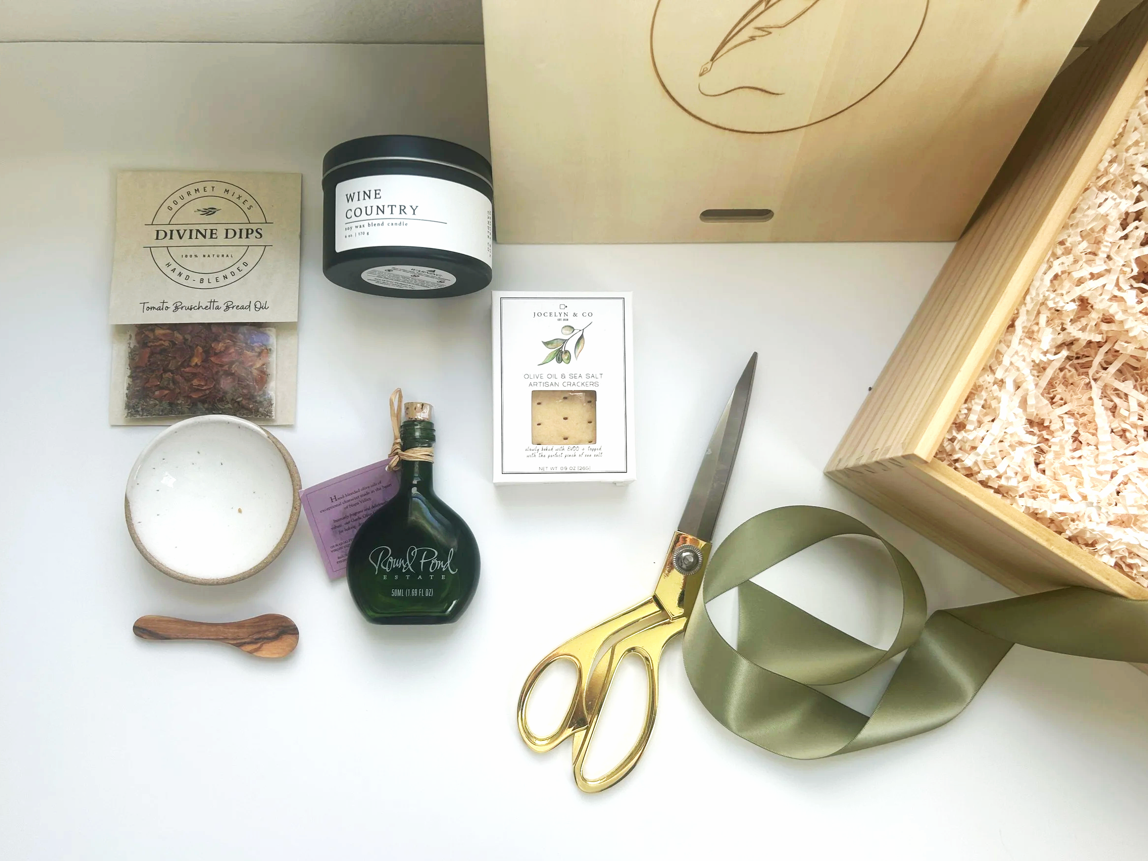 A gift box contains holuday tea, an evergreen trail candle jar of wildflower honey and mug and california candied pecans with a gold tea spoon christmas greens and neutral crinkle paper