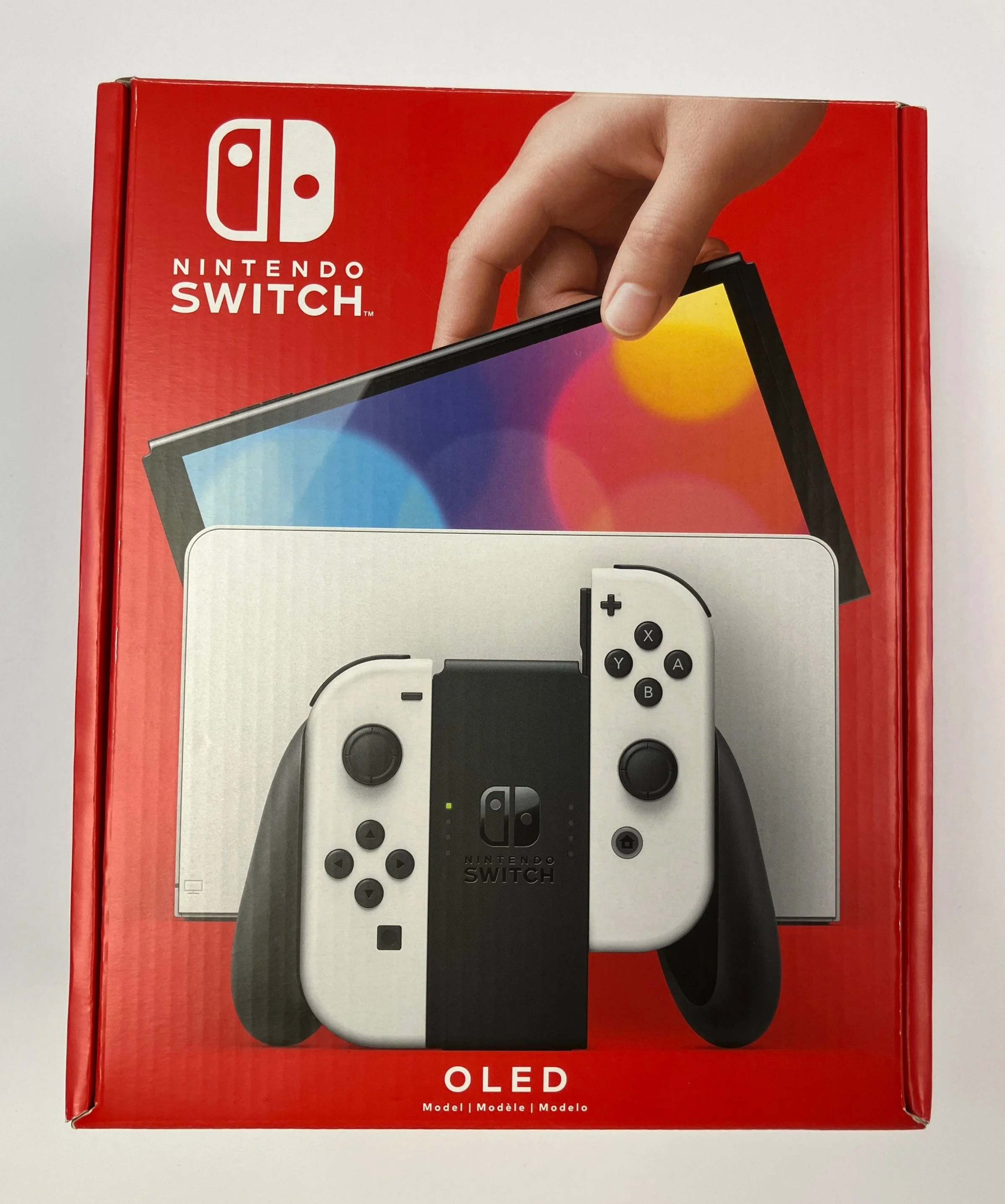 Box of a Nintendo Switch OLED model with a hand holding the device on the front of the packaging.