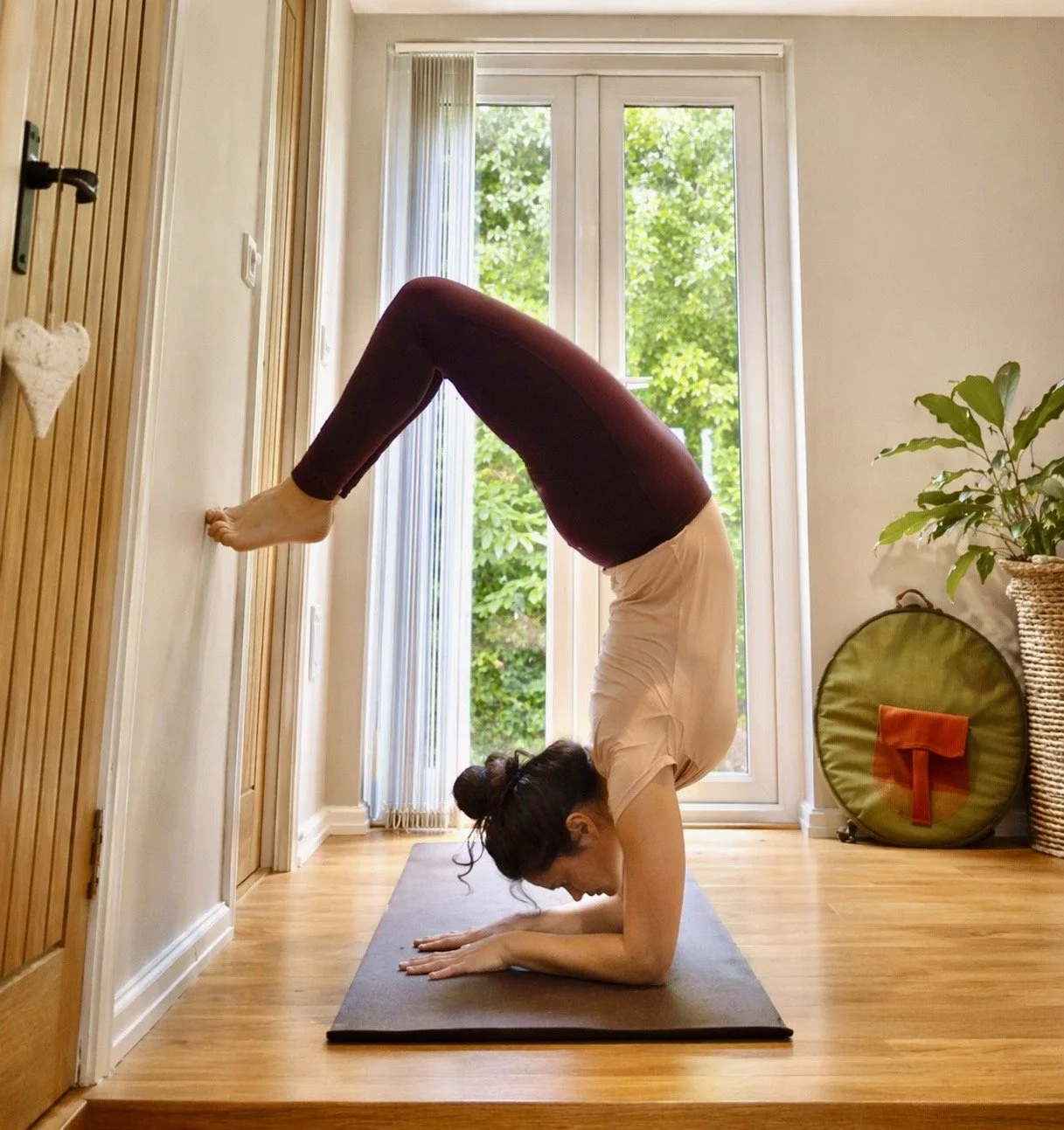 Shabnam Banihashem, yoga teacher in Pembrokeshire, demonstrating advanced yoga backbend (forearm scorpion pose) on a mat at home studio, Shabnam Yoga in Pembrokeshire UK