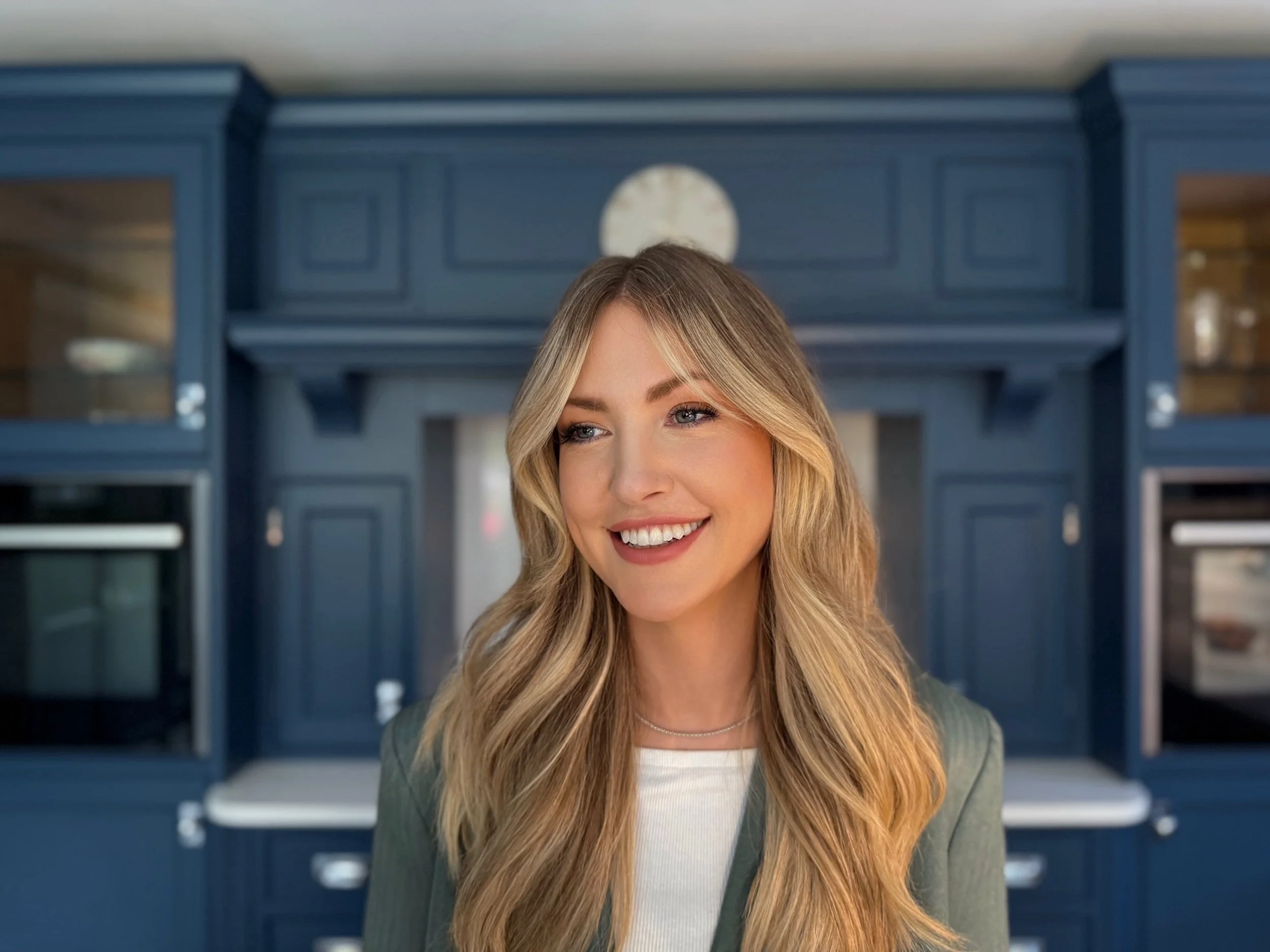 Georgina Nicole, registered nutrition therapist in Gibraltar, smiling in front of blue kitchen cabinets
