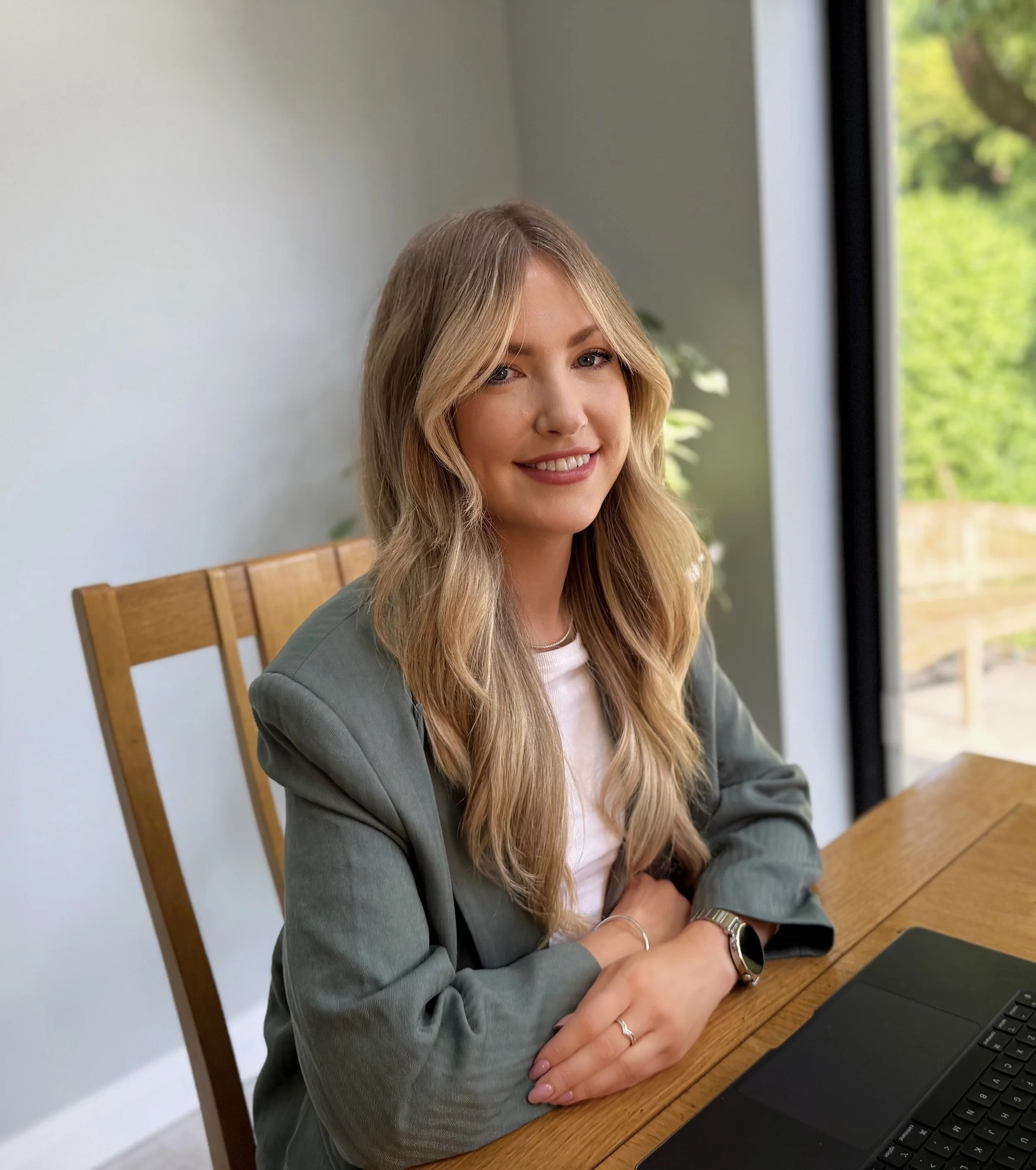 Georgina Nicole, registered nutrition therapist, sitting at a desk with a laptop, smiling at camera