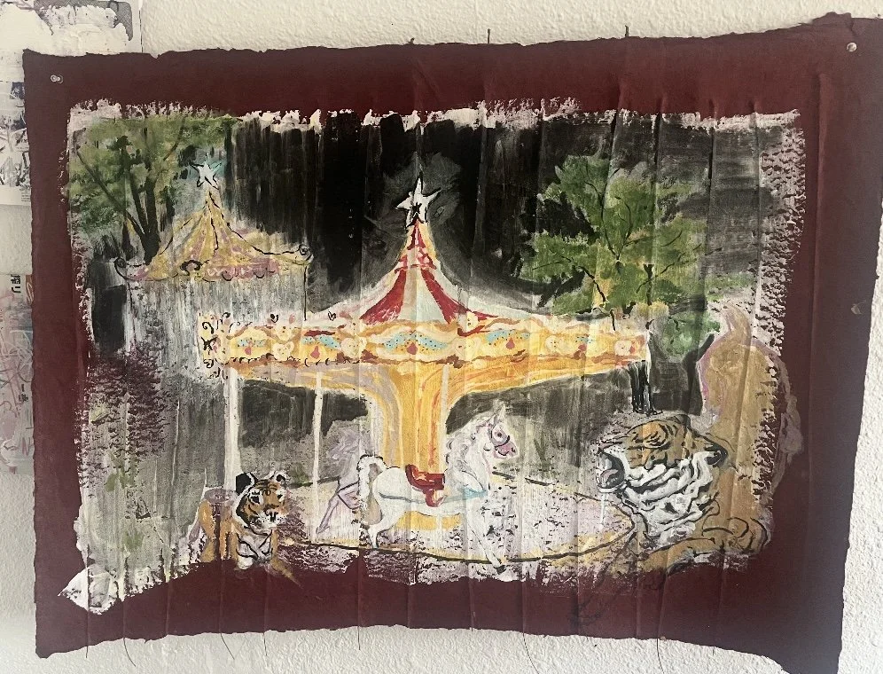 Hand-painted picture of a carousel with three white horses, surrounded by trees and two tigers, one sitting and one lying down.