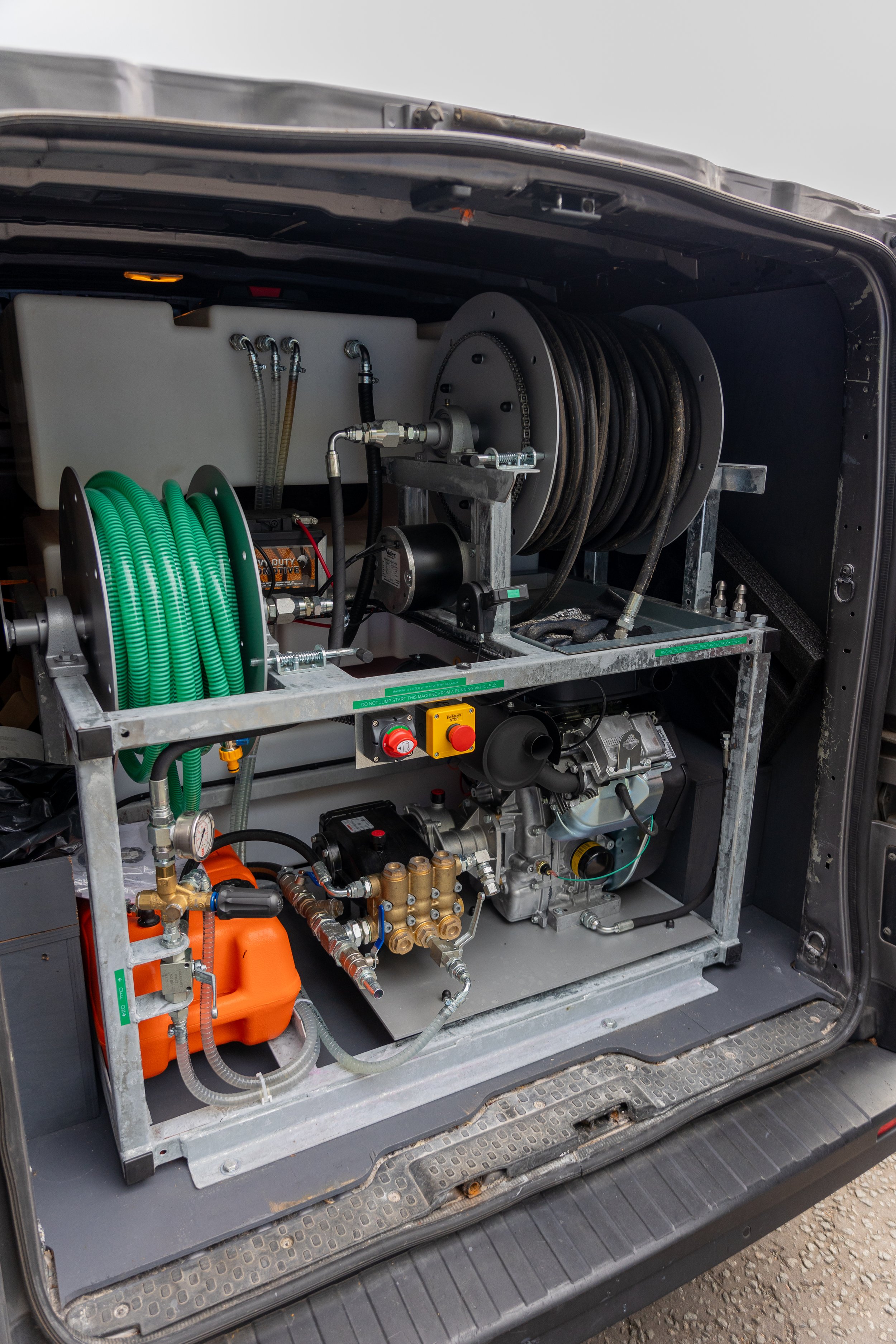 Industrial water pump system with hoses, valves, and electrical components inside a vehicle