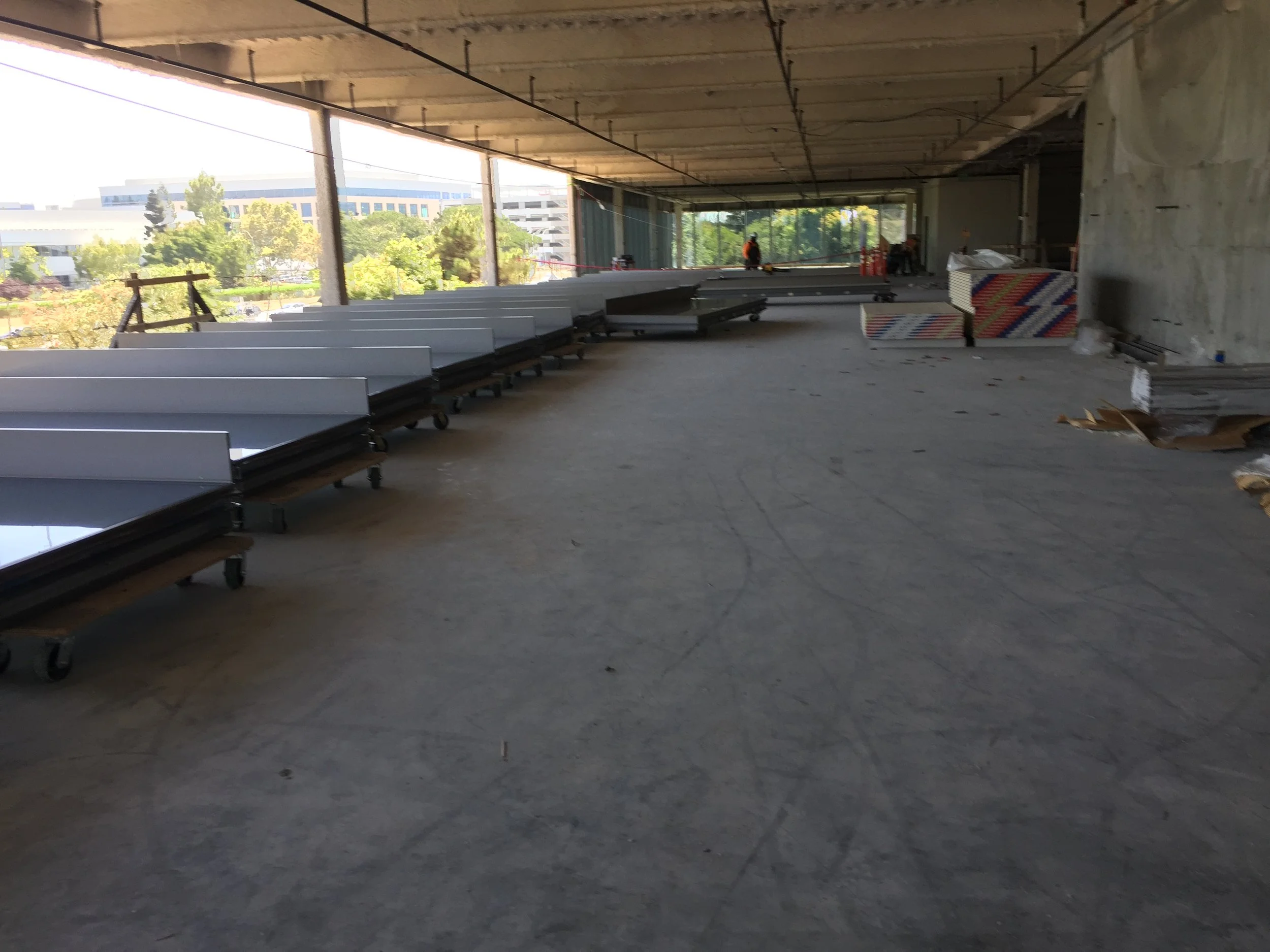 Unfinished interior floor of a commercial building with stored decking panels and visible concrete slab, representing conditions during evaluation.