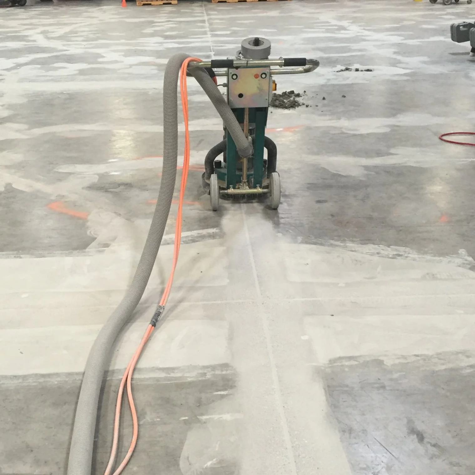 Floor grinder leveling an epoxy repaired band on a warehouse concrete slab.