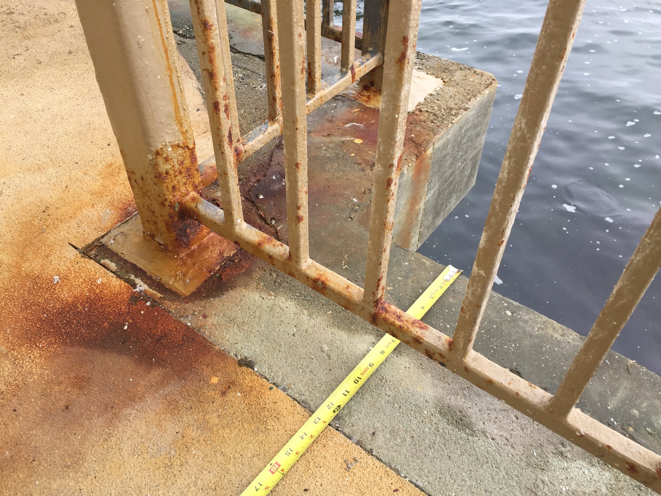 Severe corrosion at a railing base due to chloride exposure. Highlights structural risks and need for protective maintenance.