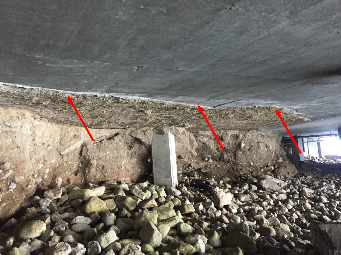 Severe soil erosion beneath a concrete slab, exposing structural risks. Highlights the impact of coastal conditions on foundation stability.