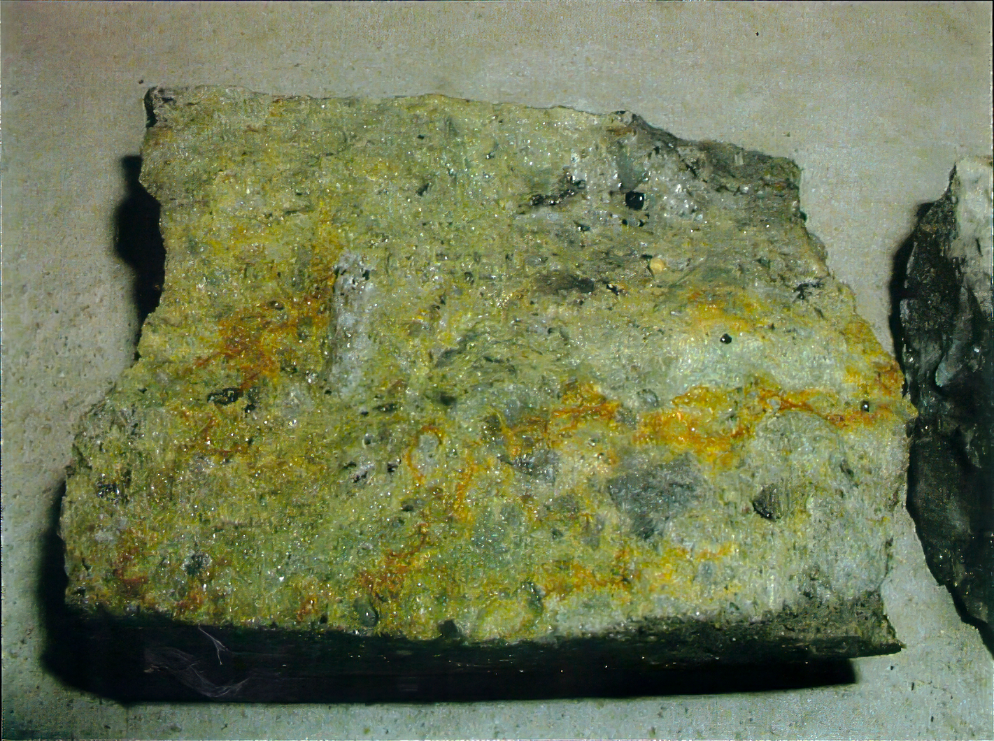 Discolored concrete core sample from a reinforced concrete tunnel wall showing yellow-brown staining and internal material condition.