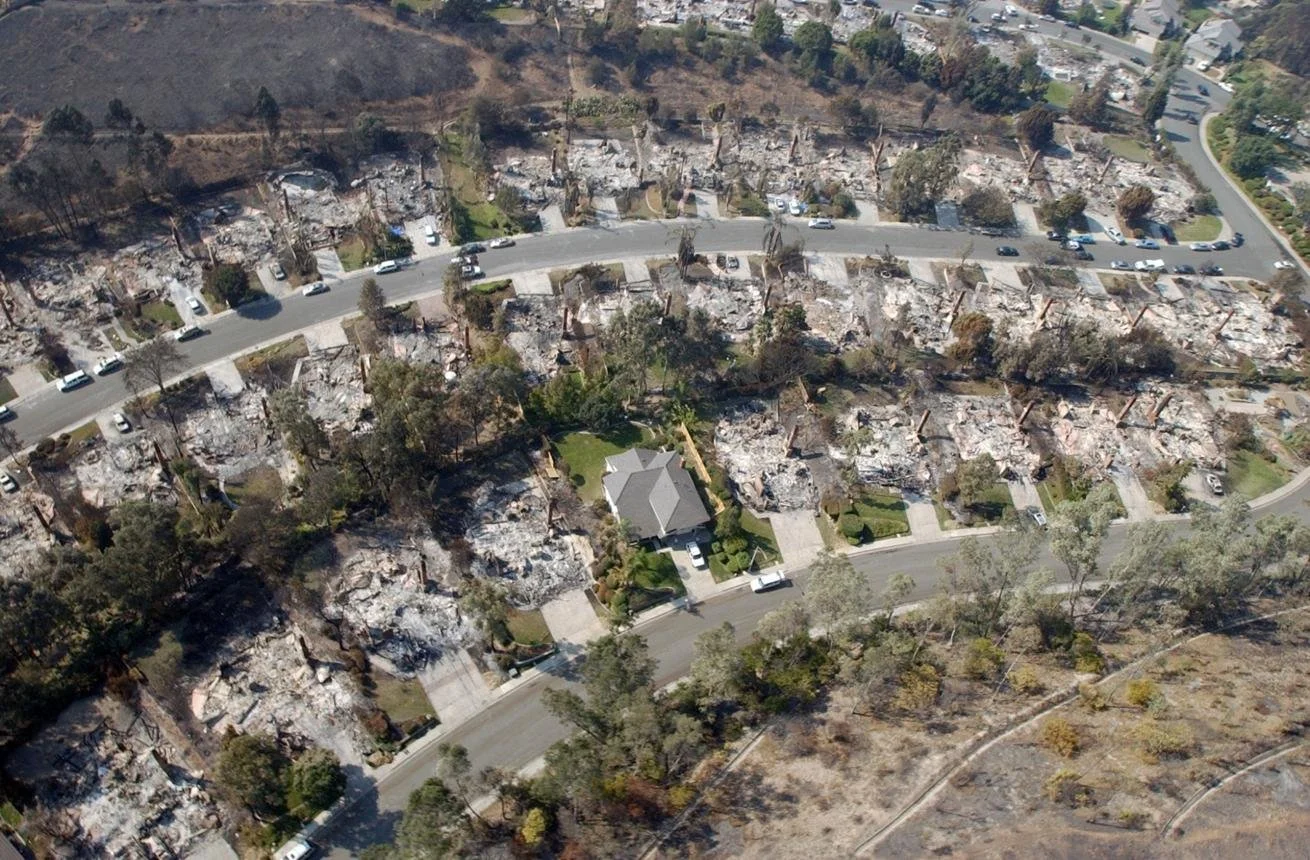 Aerial view of a California neighborhood damaged by wildfire, illustrating how wildfire impacts residential communities and defensible space planning.