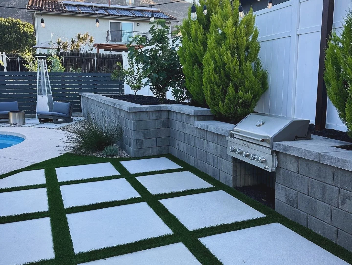 Modern outdoor kitchen and poolside patio with custom hardscape