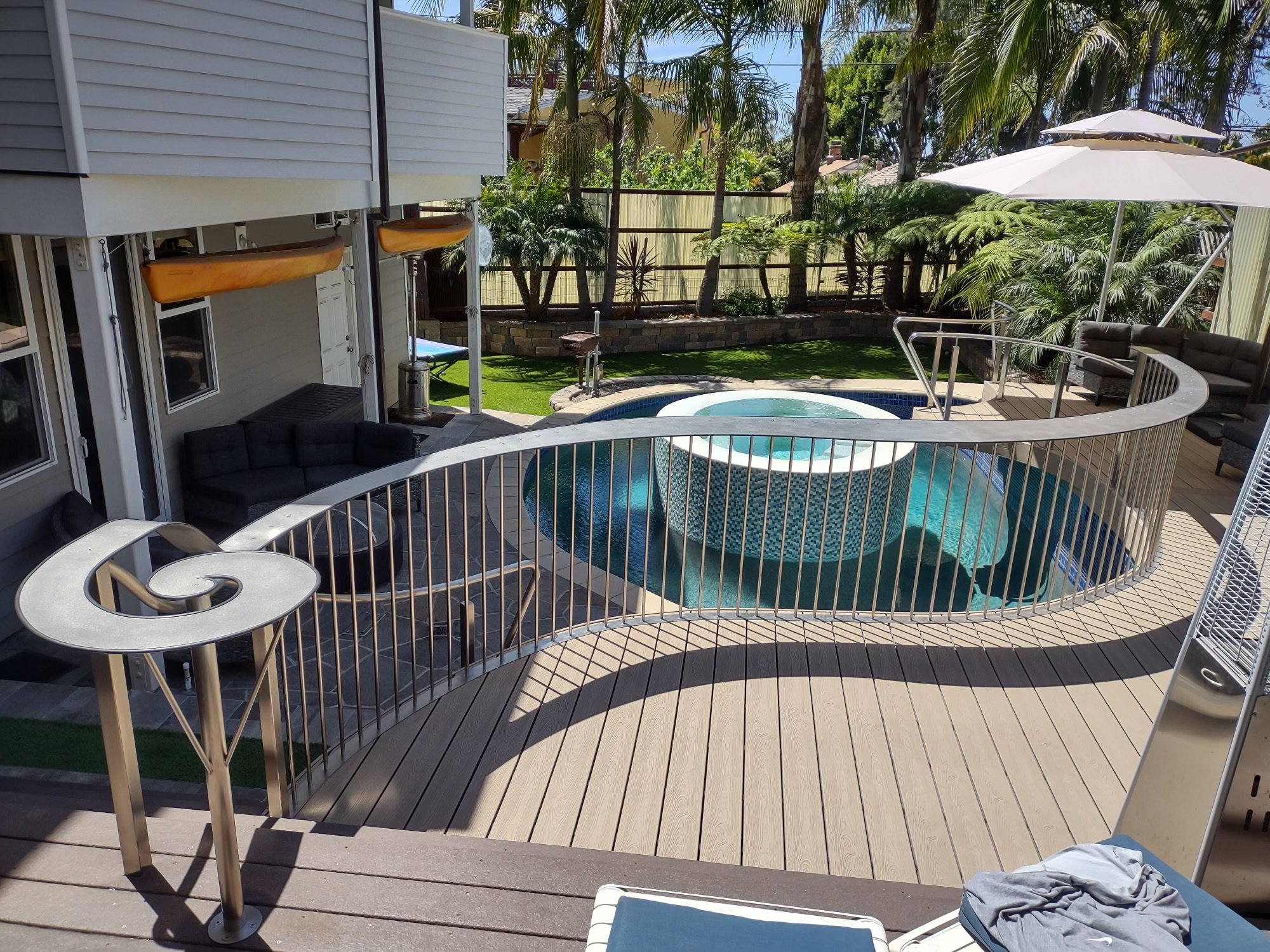 Pool decking made out of a composite material with the stainless steel railing around a pool. Best landscape pool design.