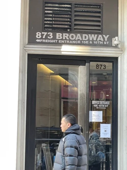 Person walking past a building at 873 Broadway