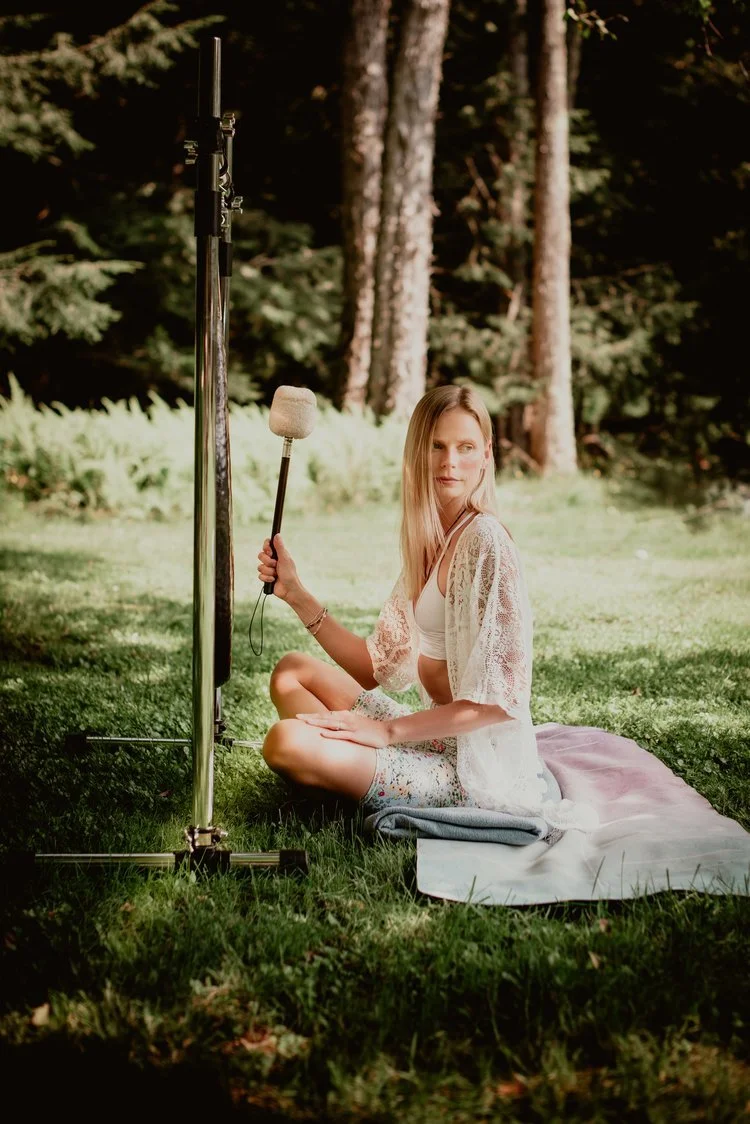 Irene sitting on a blanket in a forest, holding a microphone, with recording equipment nearby.