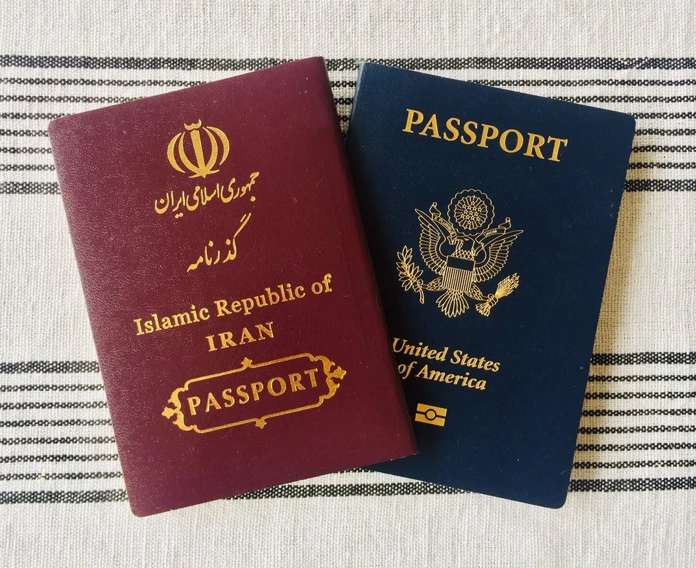 Two passports on a striped fabric surface, one from Iran and one from the United States.