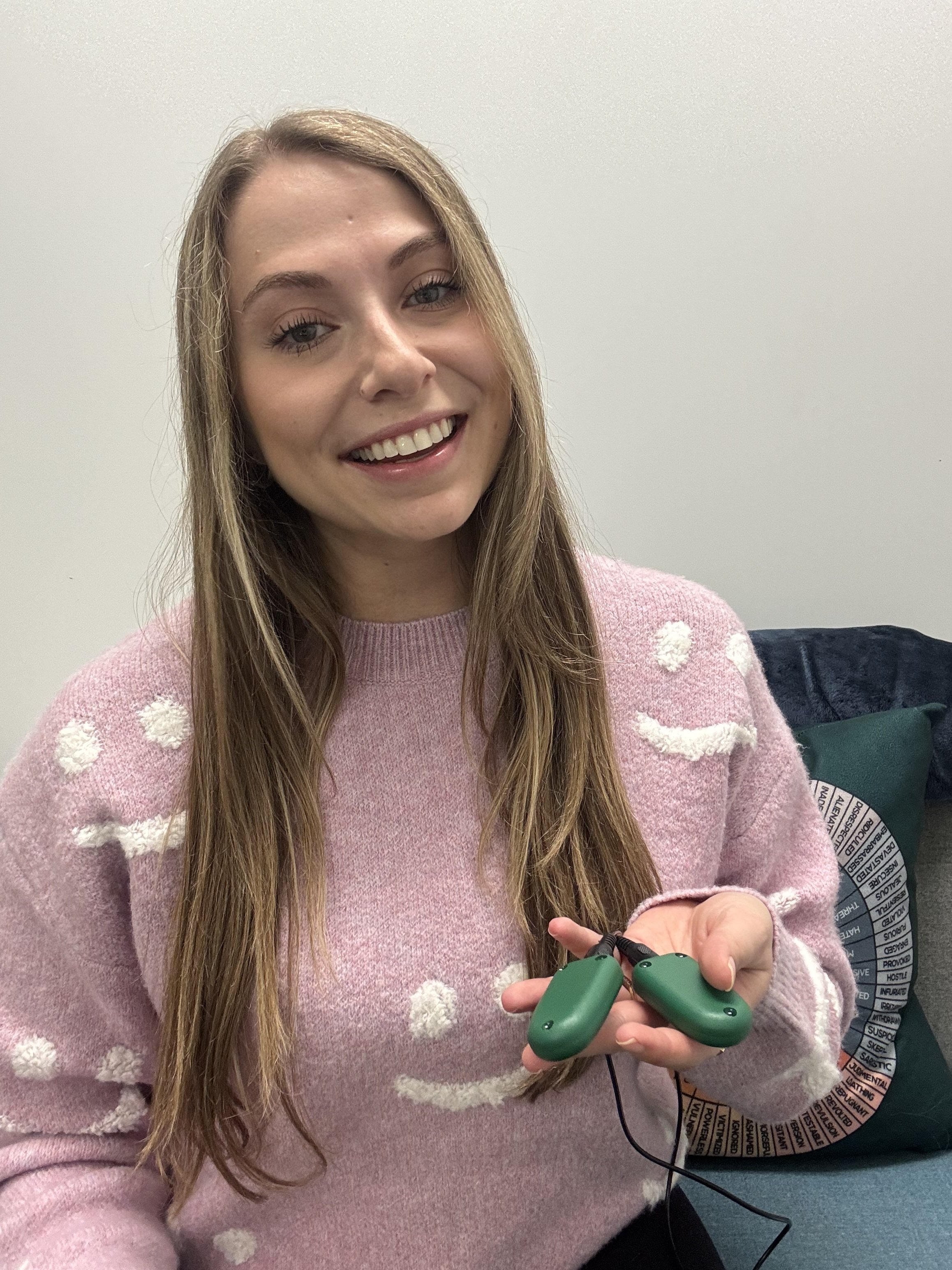 Therapist wearing pink sweater holding EMDR tappers