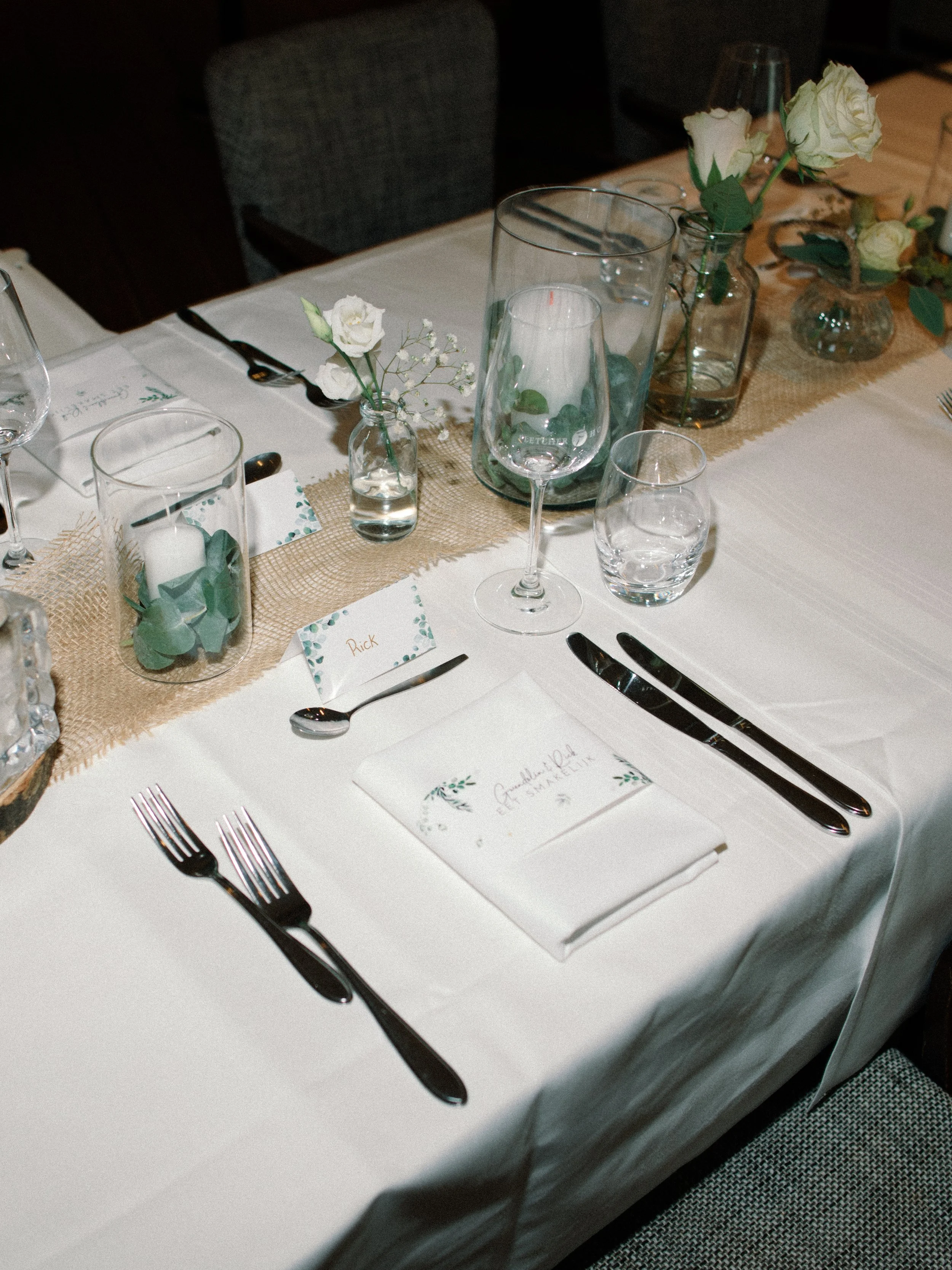 Feestelijk gedekte tafel met zwart bestek, wijnglazen, kaarsen en witte bloemen in glazen vaasjes-trouwfotograaf-assen-groningen-drenthe