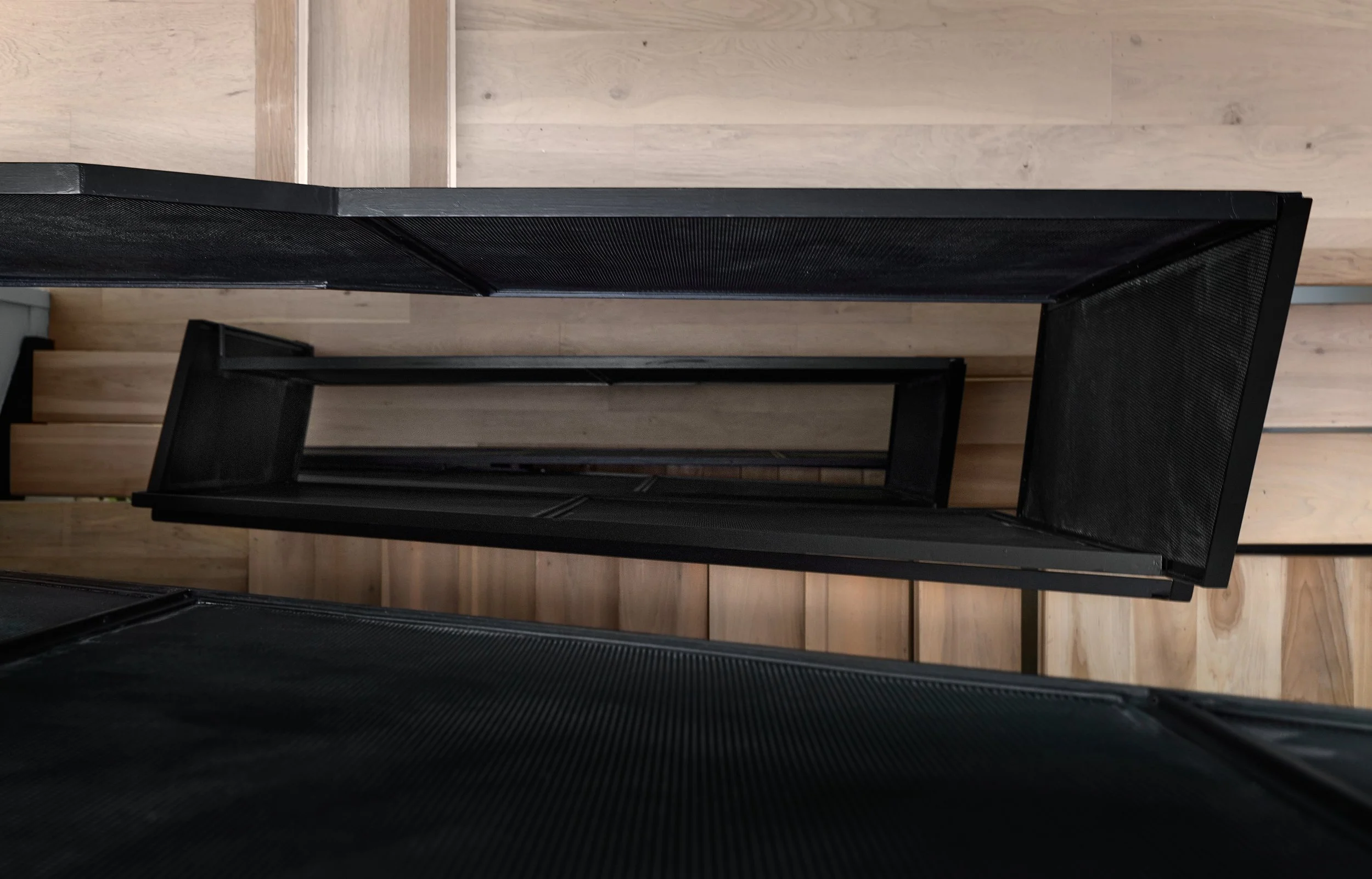 Looking down on a spiral staircase with black metal steps and wooden walls.