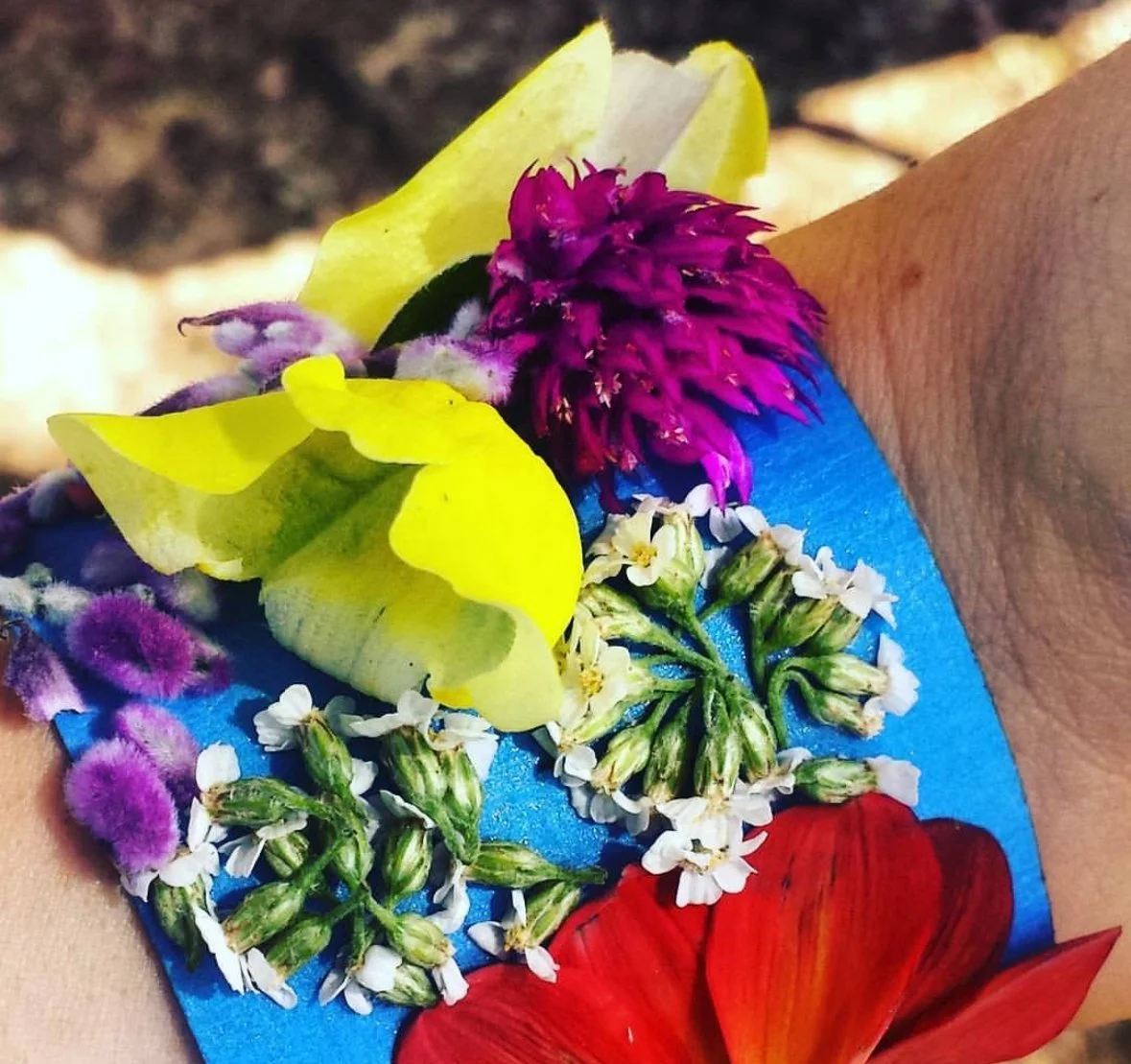 Colorful flower bracelet with yellow, purple, pink, white, red, and blue flowers and greenery