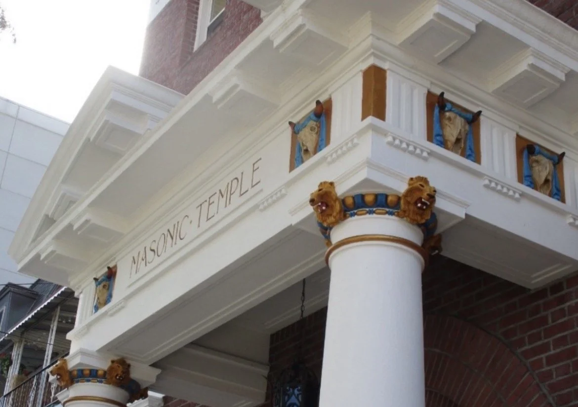 Restored façade of Advance Masonic Temple in Astoria Queens showing gold detailing columns lions and entrance doors
