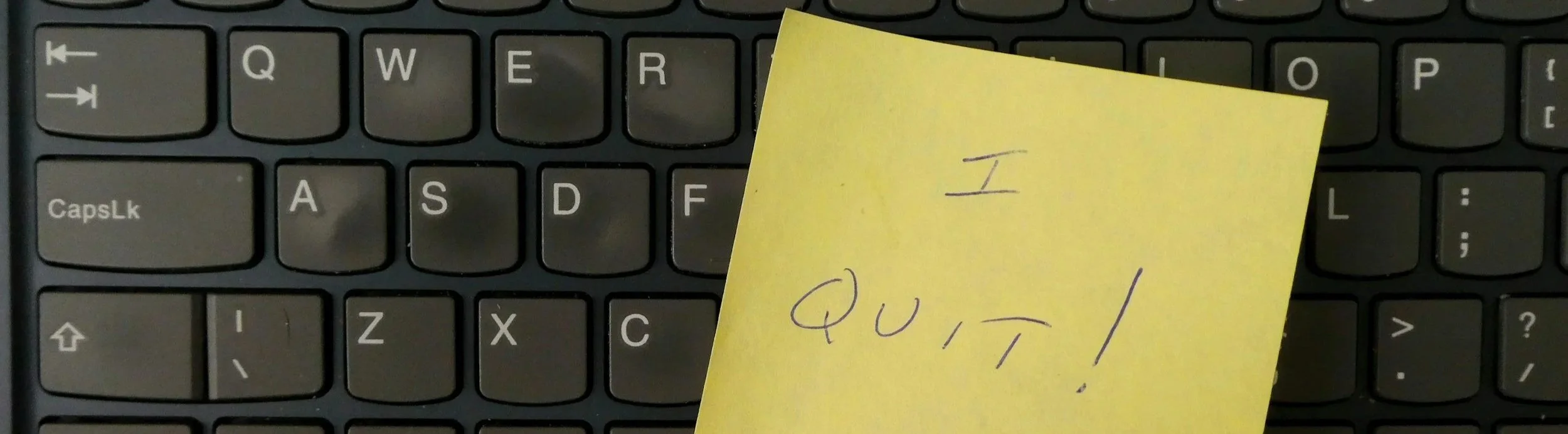 A sticky note reading "I Quit" on a keyboard, representing the cost of avoided conversations in the workplace.